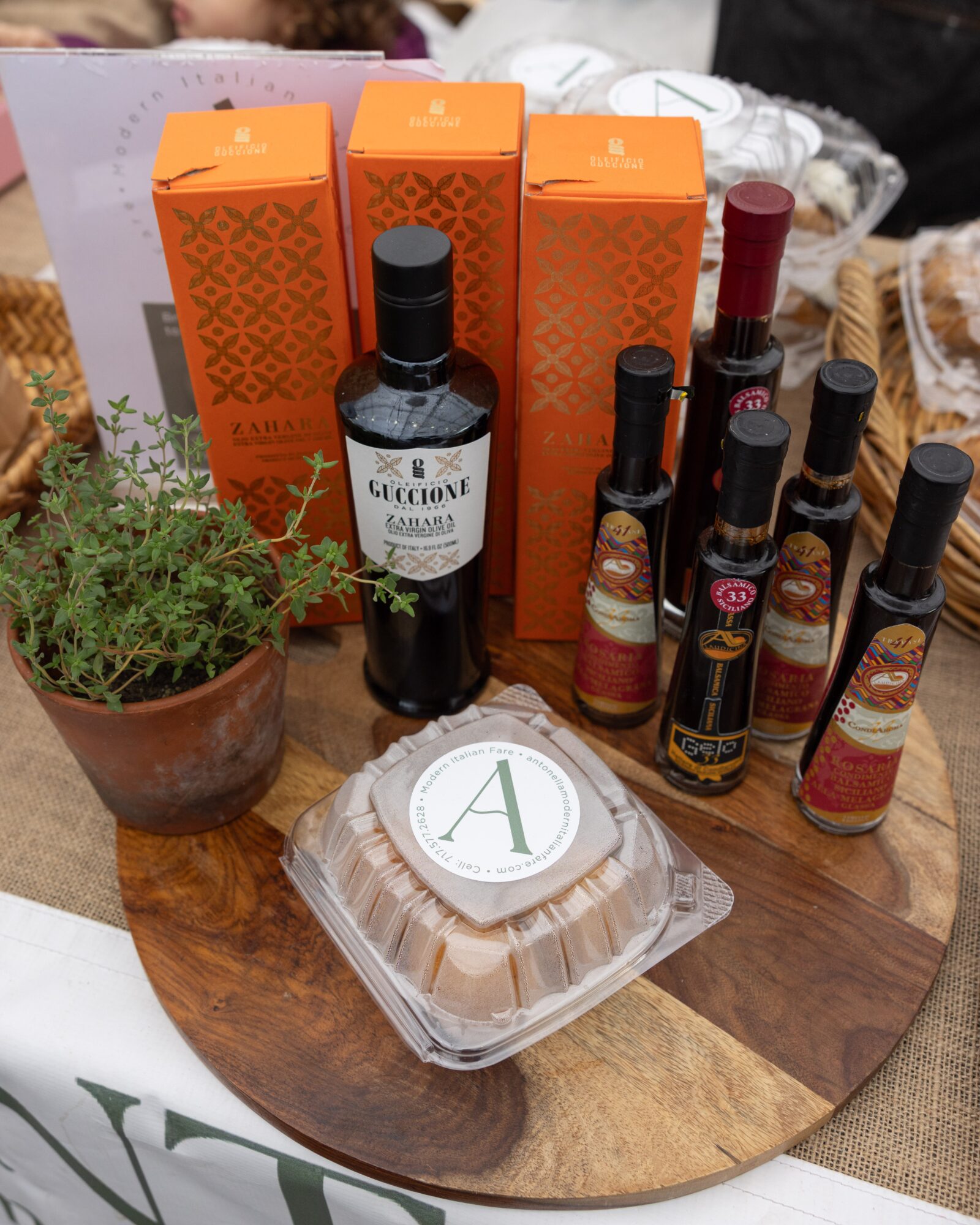Assorted bottles, boxes, a potted plant, and a container with a letter A on a wooden surface.