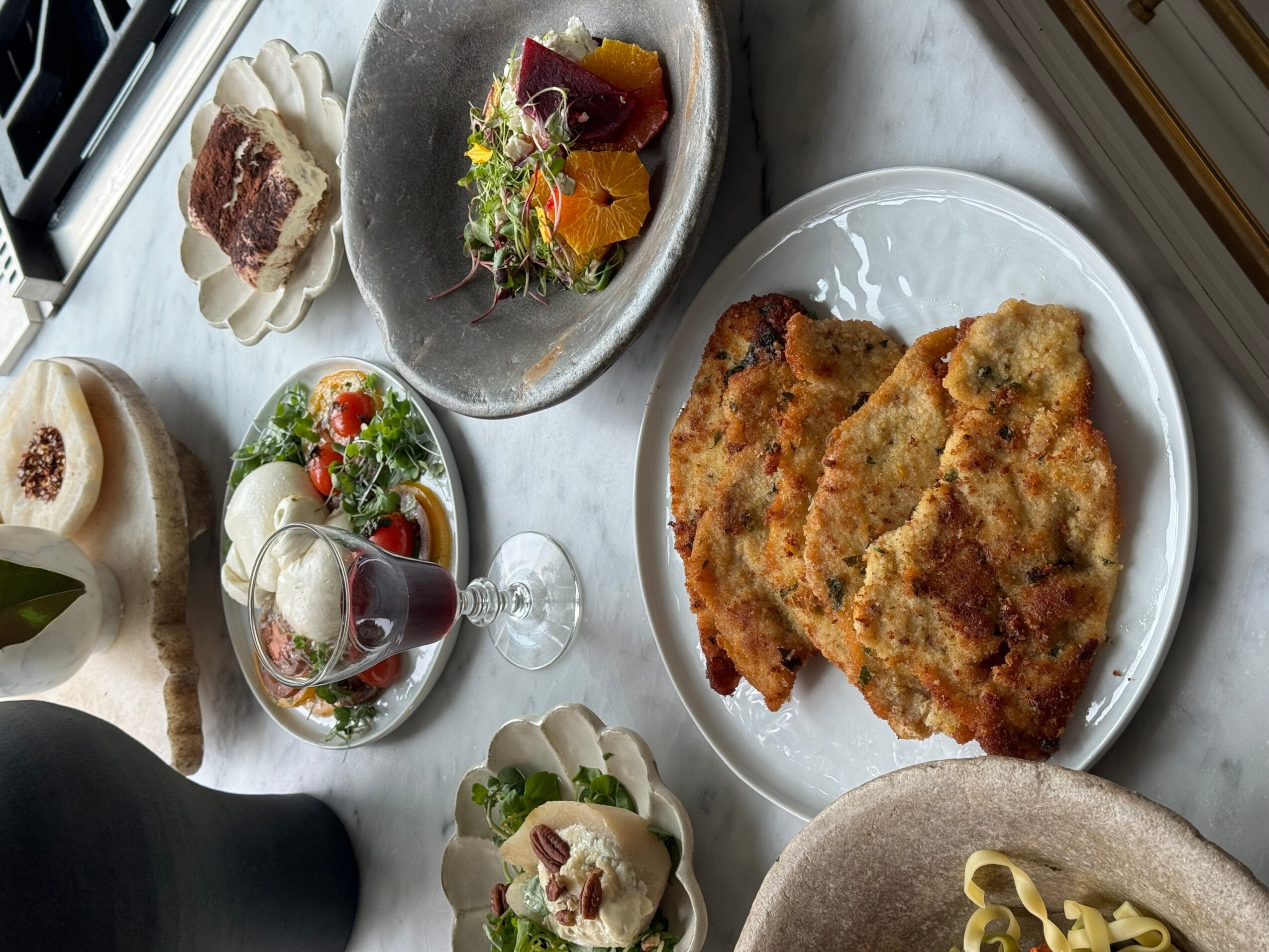 Assorted dishes including fried food, salad, and desserts on plates and a glass, viewed from above.