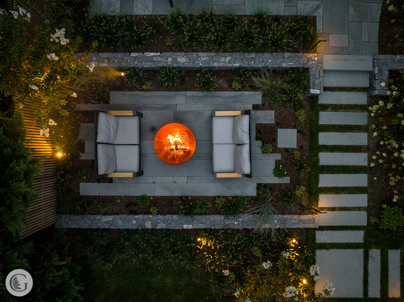 Top-down view of an outdoor seating area with two chairs, a round fire pit, and a pathway with stepping stones.