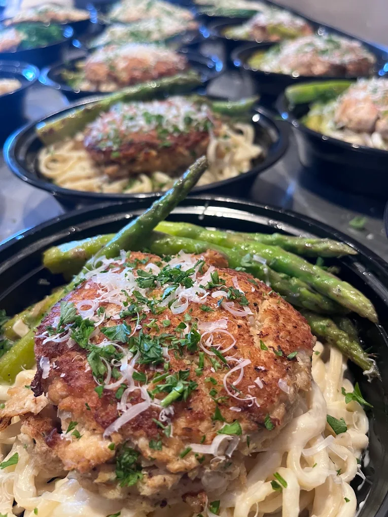 Close-up of a plate with a breaded meat patty, green beans, and shredded vegetables, garnished with herbs.