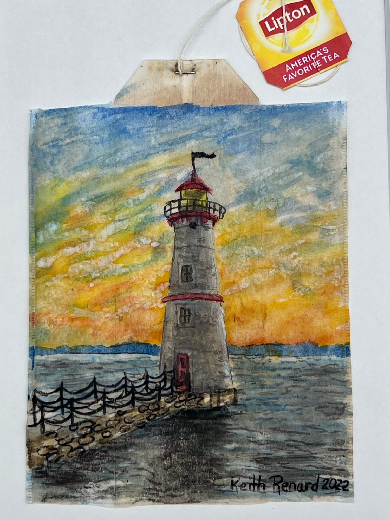 Watercolor painting of a lighthouse at sunset with a sky of orange, yellow, and blue, and a fence along the water.