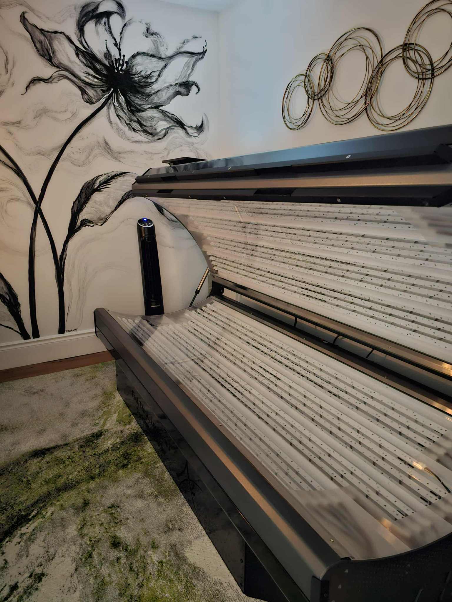 A piano with sheet music on the stand, a wall with a large flower drawing, and a row of circular wall decorations.