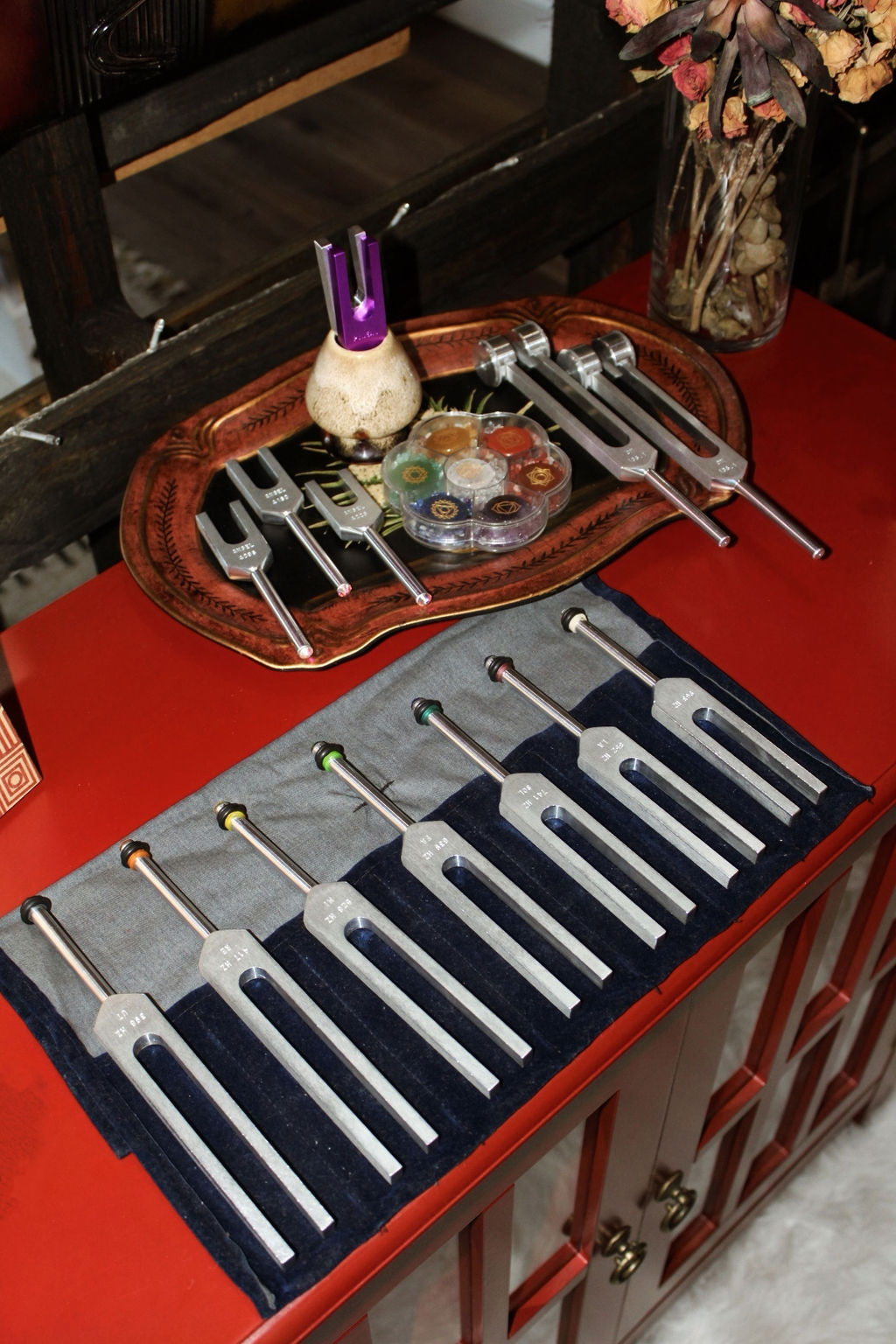 Table setting with cutlery, a decorative bowl, and a vase with flowers on a red tablecloth.