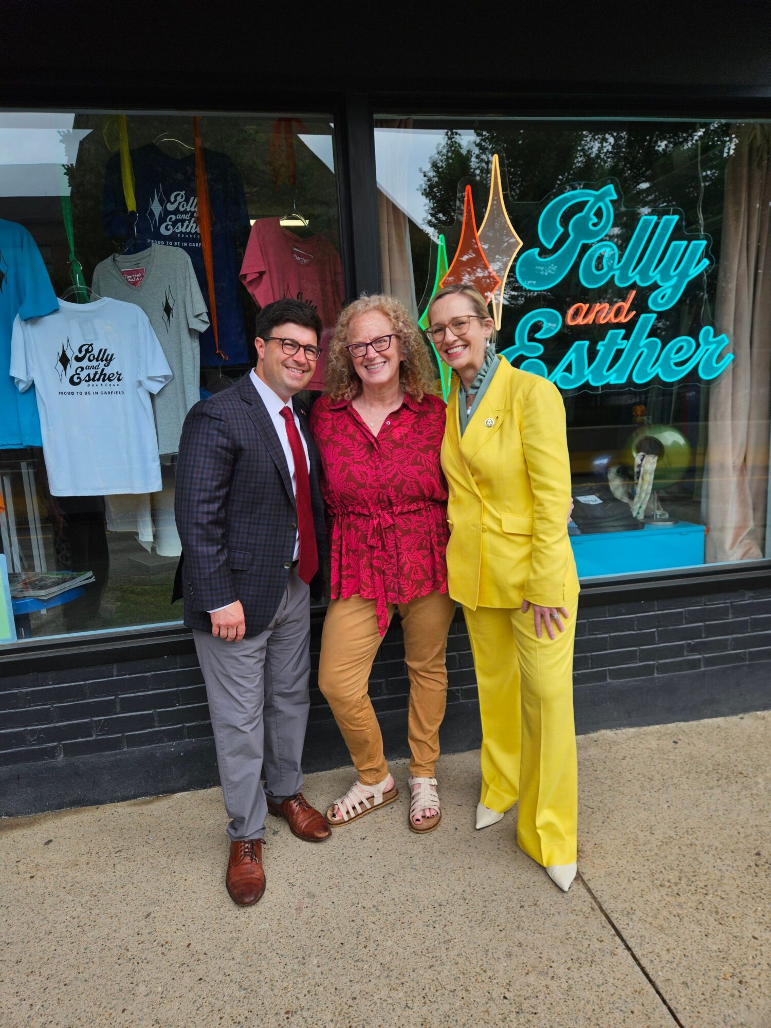 Three people standing outside a storefront with a sign that reads