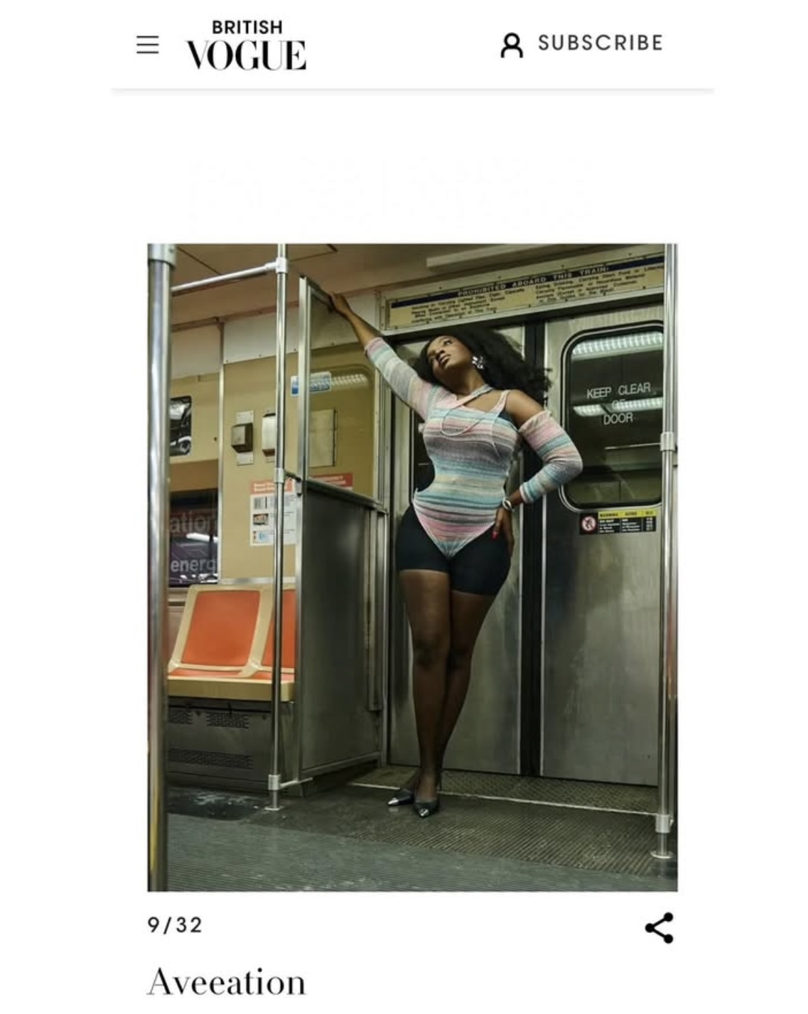 Person standing in a subway train, holding onto a pole, wearing a striped top and shorts.