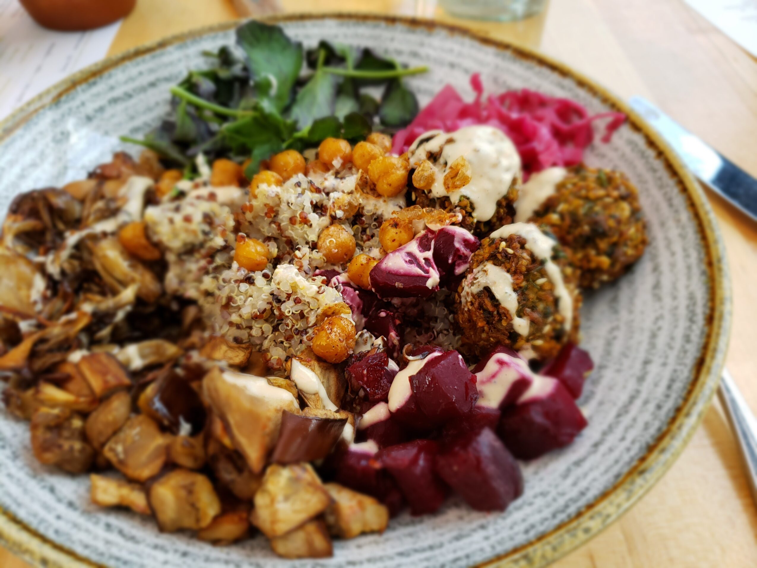 Plate with various foods including salad, grains, vegetables, and possibly meat or protein items, on a table.