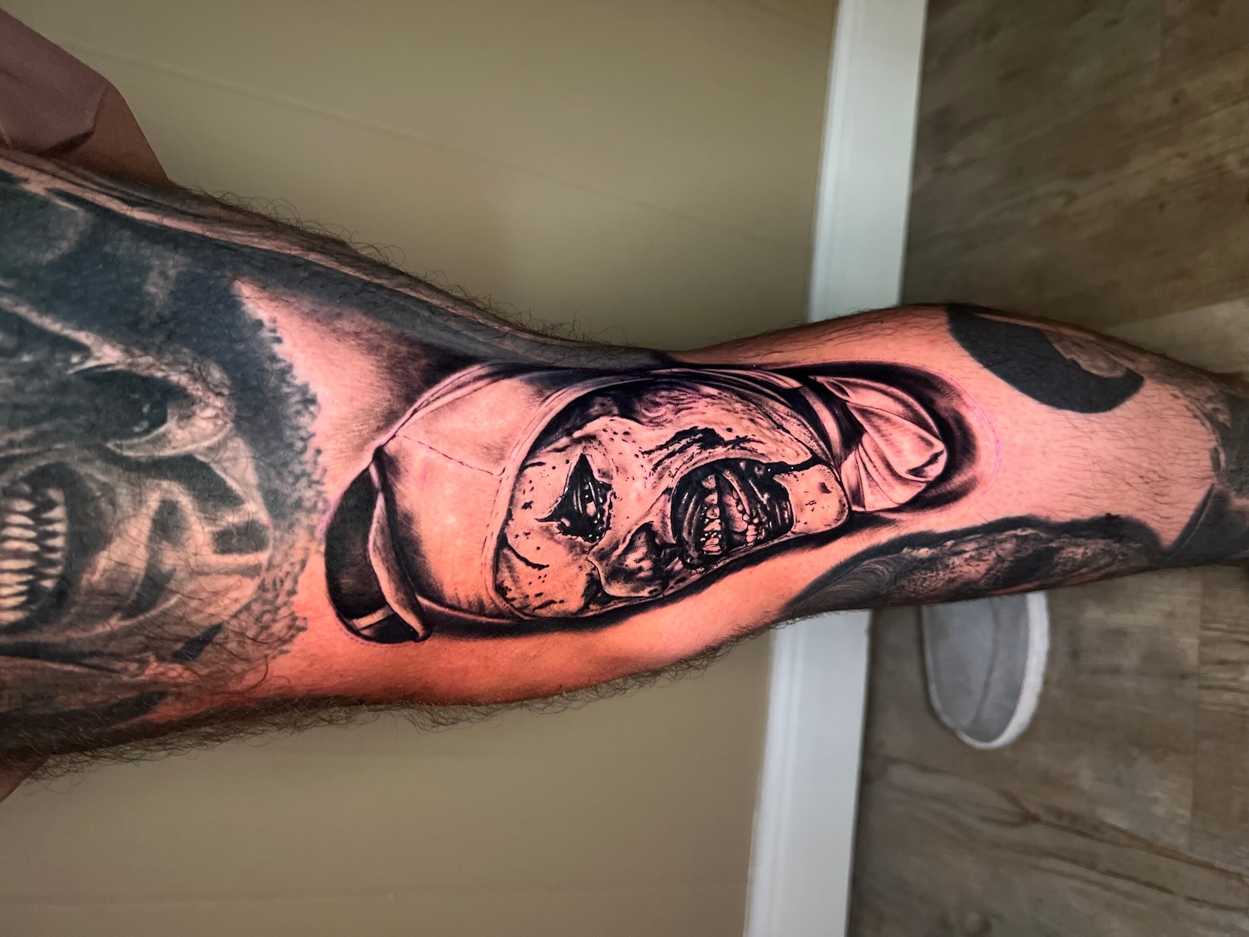 Tattoo of a dog's face on person's arm, with detailed shading and realistic features.