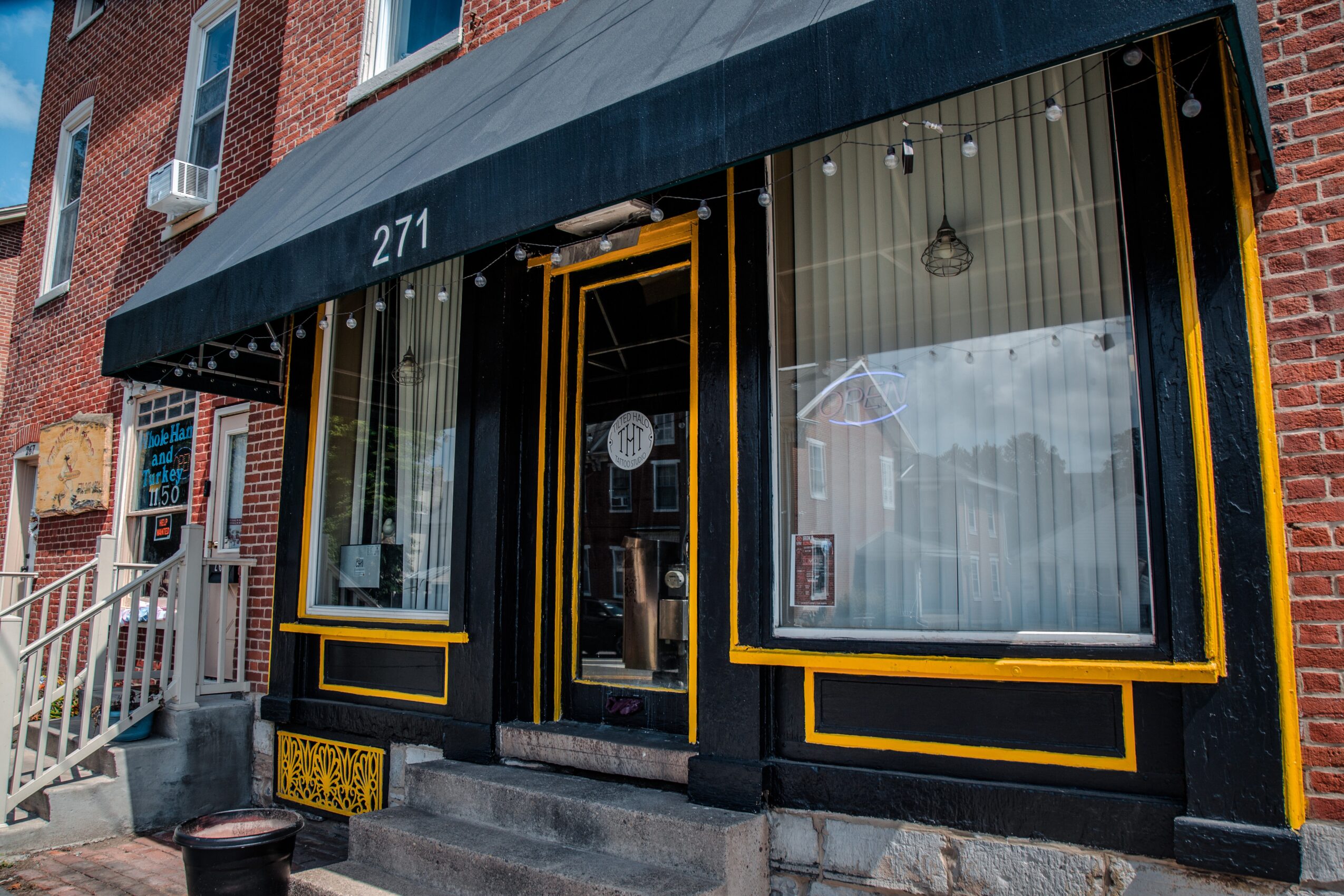 Storefront with black and yellow trim, glass door, and large window, located at 271, with steps leading up to entrance.