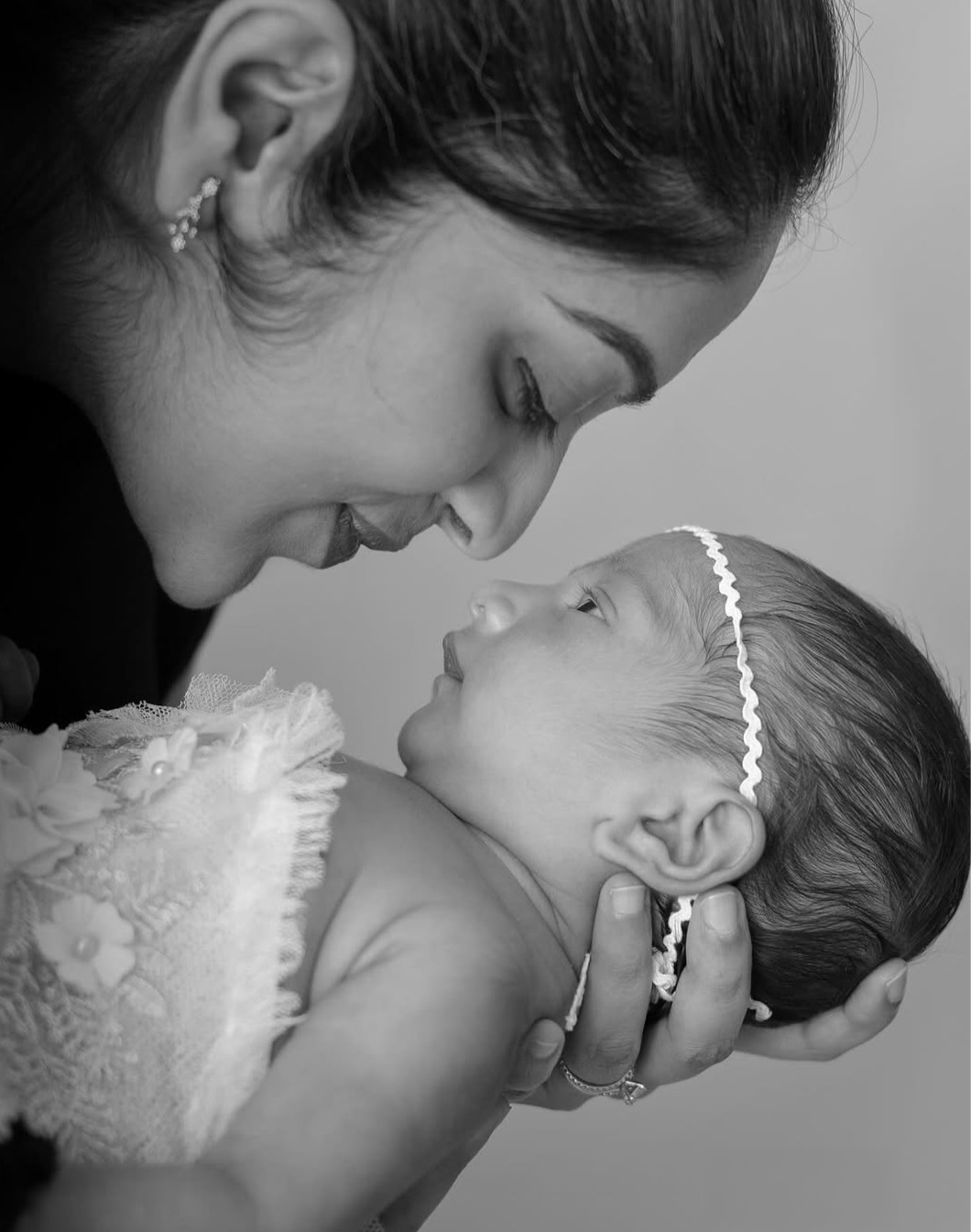 Woman holding a newborn baby close, both looking at each other, in black and white.