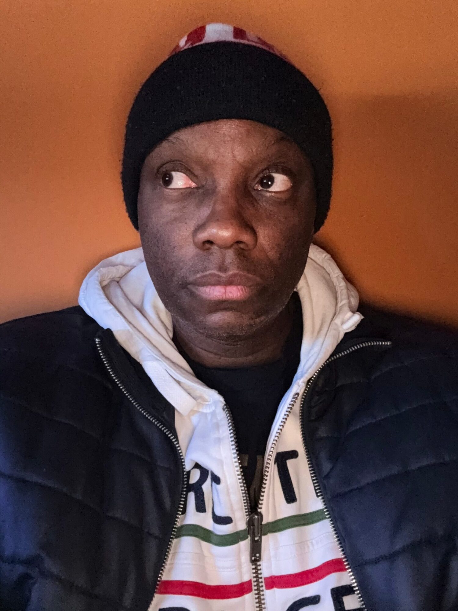 Person wearing a black beanie and white hoodie, looking at the camera with a neutral expression.