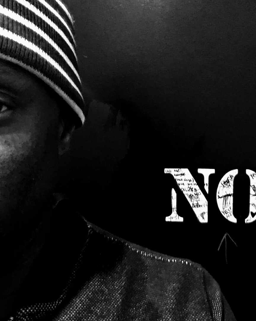 Part of a person's face wearing a striped beanie, with a dark background and partial text visible.
