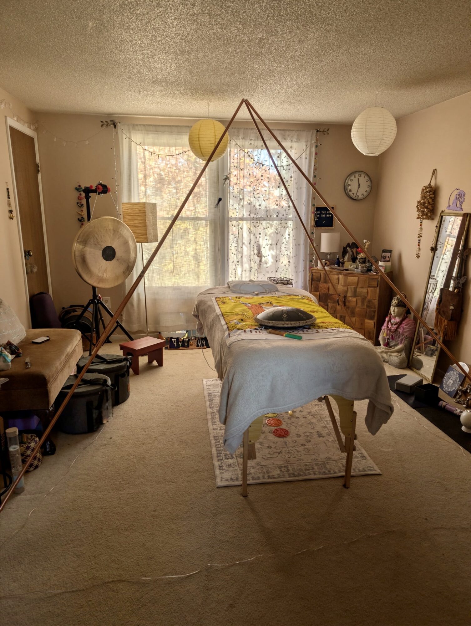 Room with a bed, large window, and various decorative items, including hanging paper lanterns and a clock on the wall.