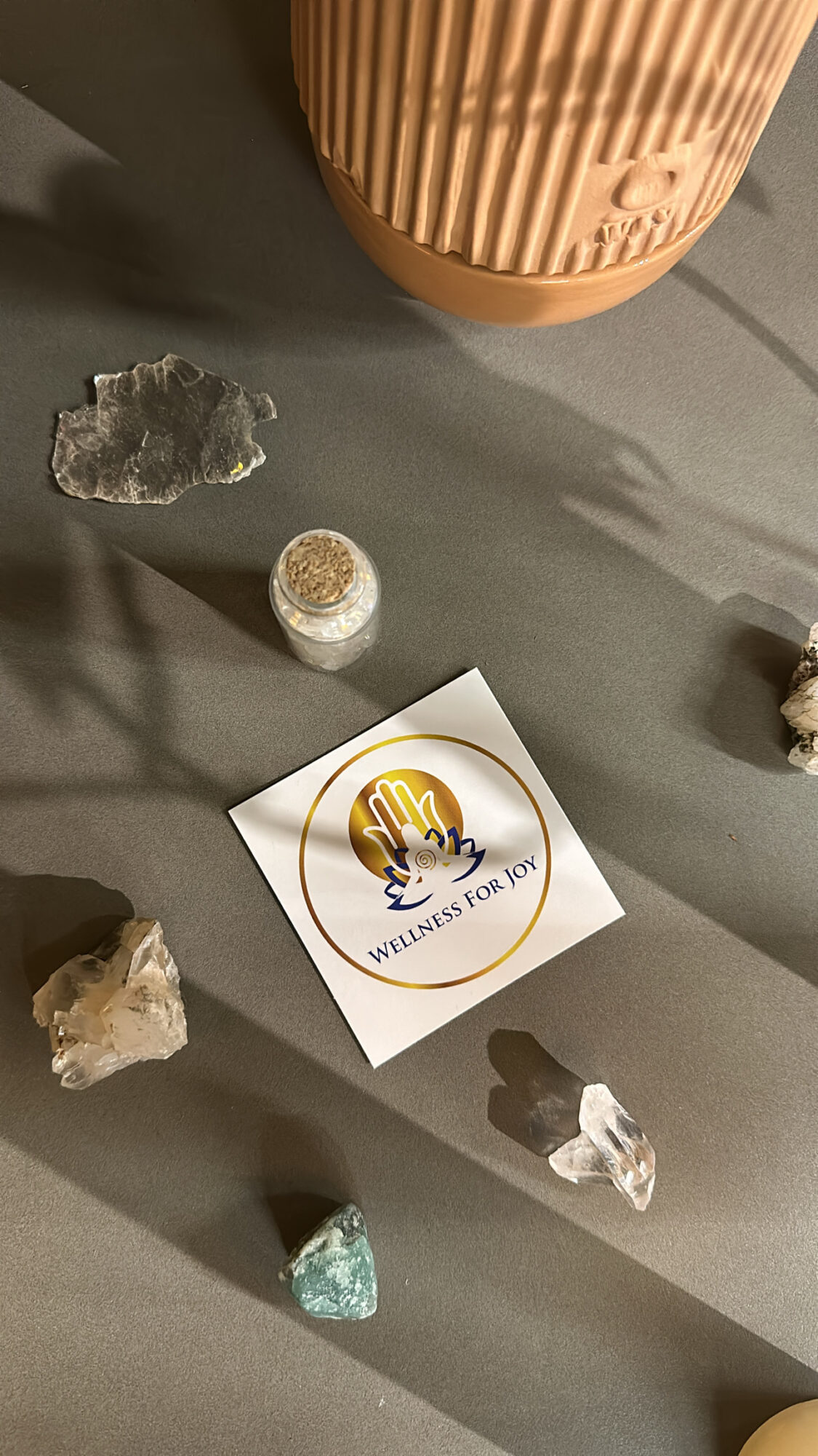 Flat surface with crystals, a sticker, and a container, with shadows cast by sunlight.