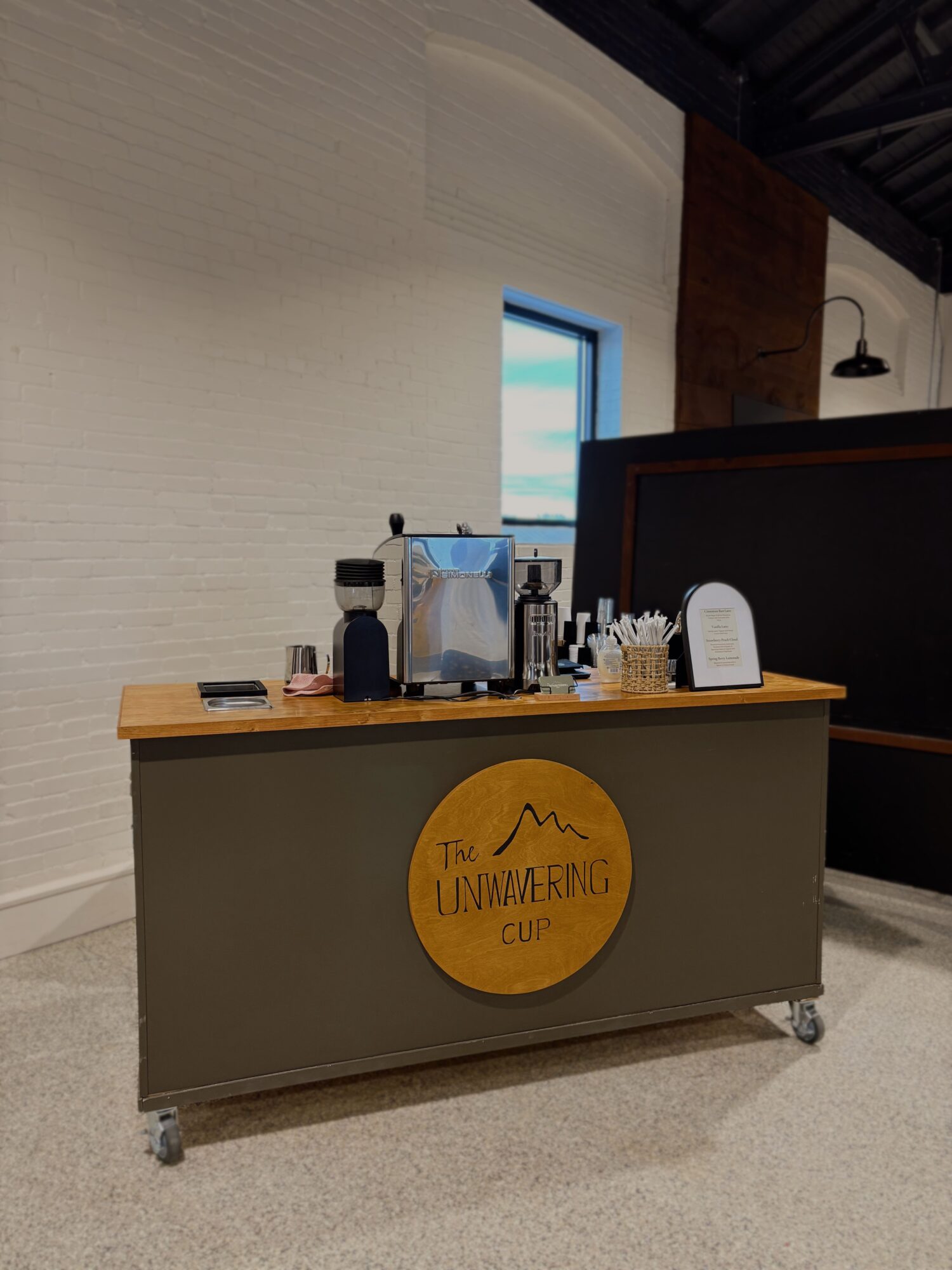 Counter with a yellow circular sign, bottles, and a small electronic device on top, against a white wall with a window.