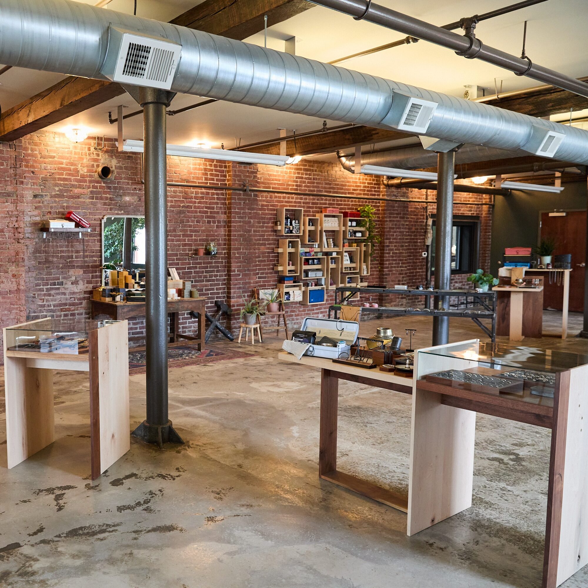 Interior of a store with brick walls, wooden ceiling beams, and display tables, some with items on top.
