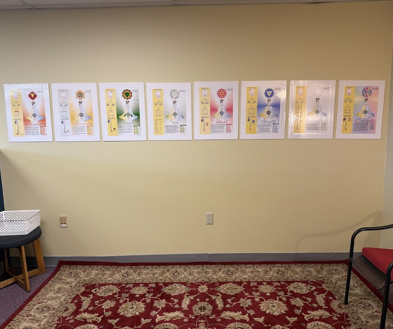 Eight posters with colorful designs and text are displayed on a beige wall, with a red and beige patterned rug on the floor.