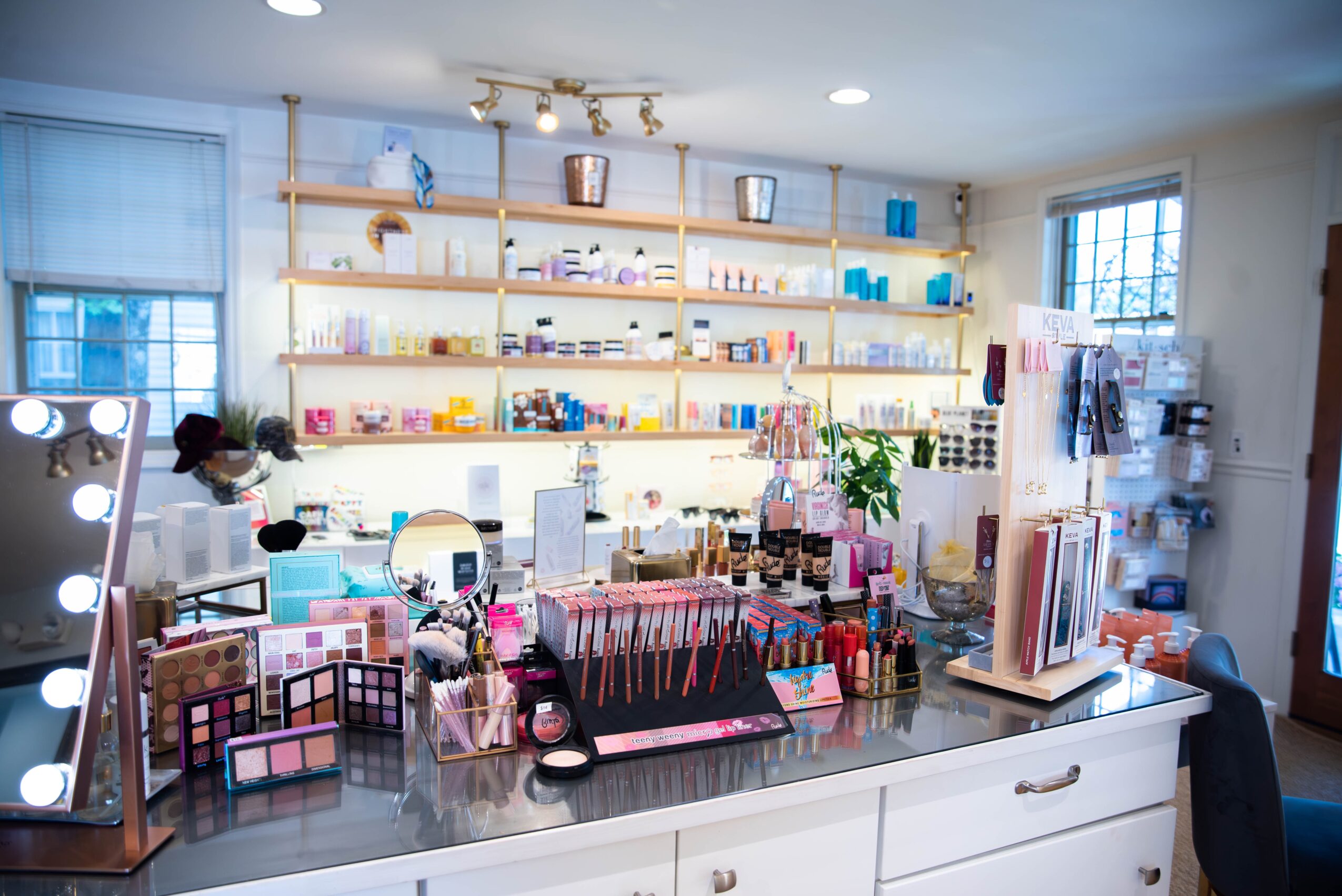 Beauty products and makeup items displayed on a white counter in a well-lit store with shelves of products in the background.
