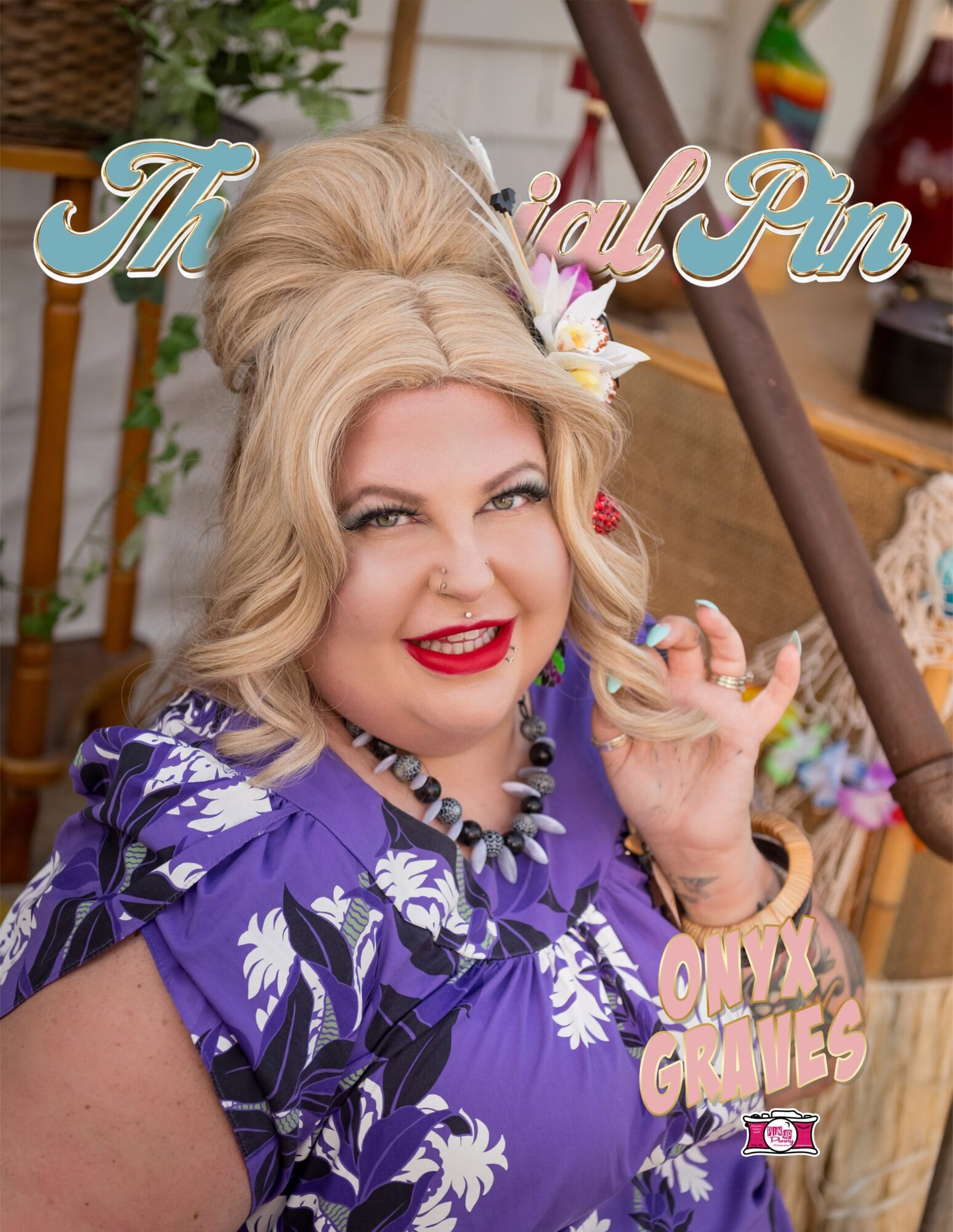 Woman with blonde hair, red lipstick, wearing a purple floral dress, smiling, holding a strand of hair, in a colorful setting.