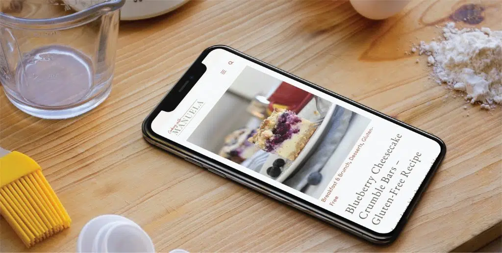Smartphone on wooden surface displaying a baking tutorial with ingredients and tools nearby.