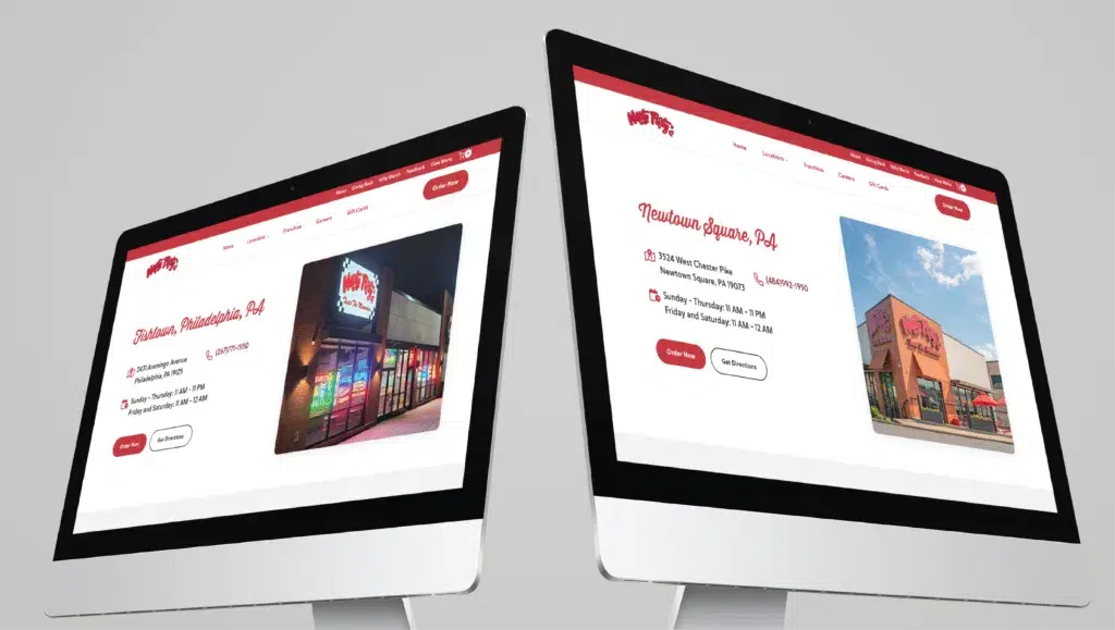Two computer monitors display websites with images of buildings and text, angled slightly away from each other.