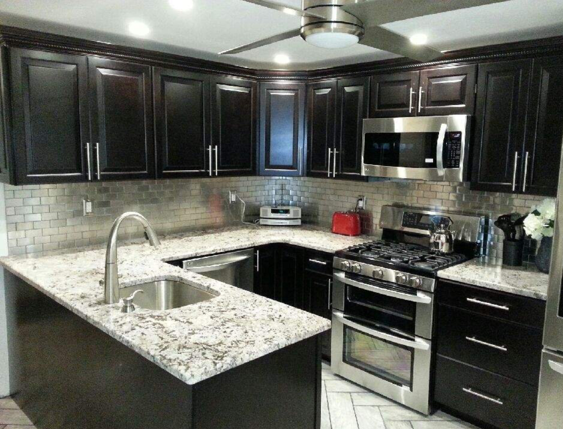 Modern kitchen with dark cabinets, granite countertops, stainless steel appliances, and a tiled backsplash.