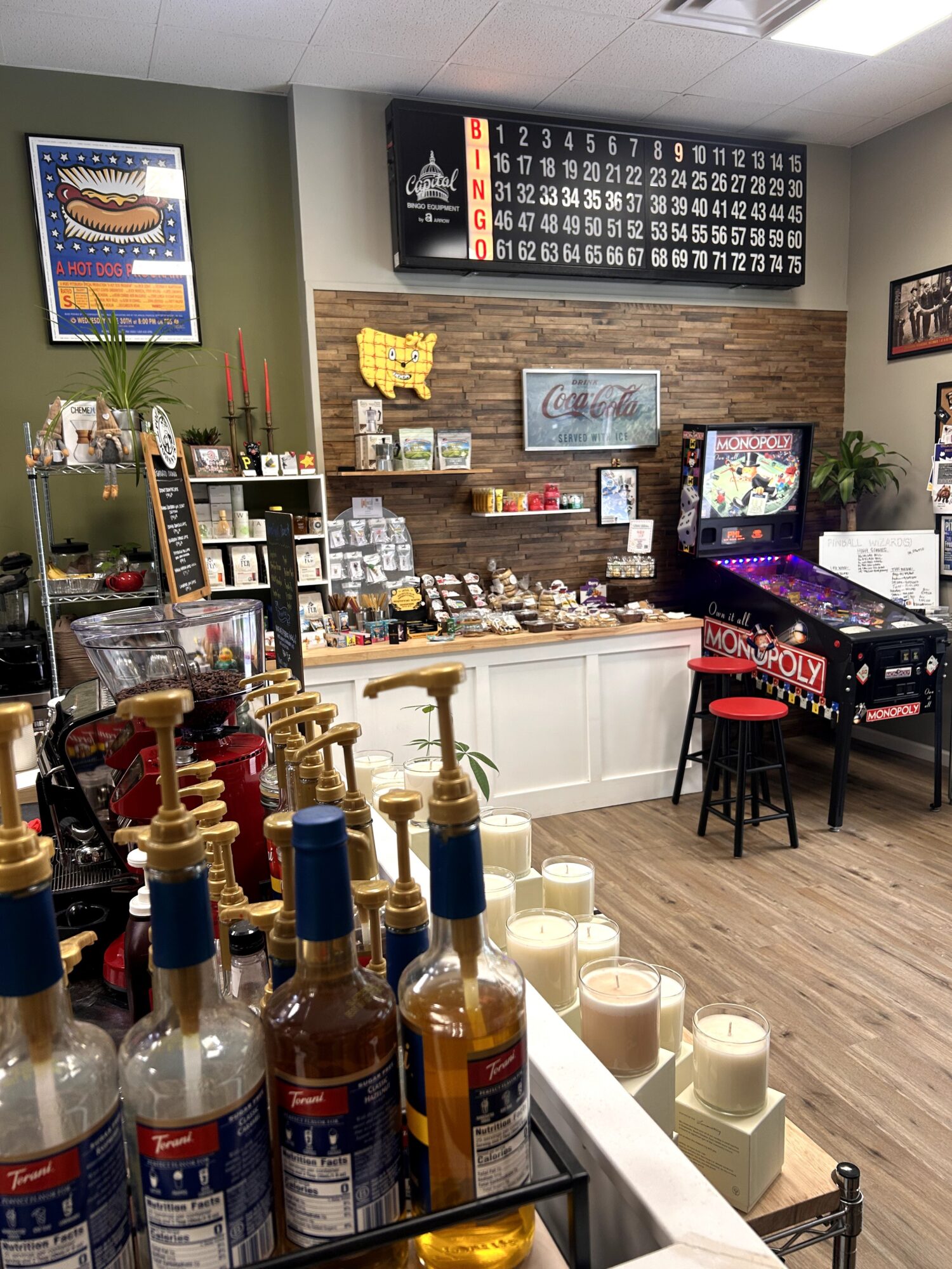 Interior of a shop with a piano, shelves of products, and decorative items, wooden flooring, and a brick wall background.