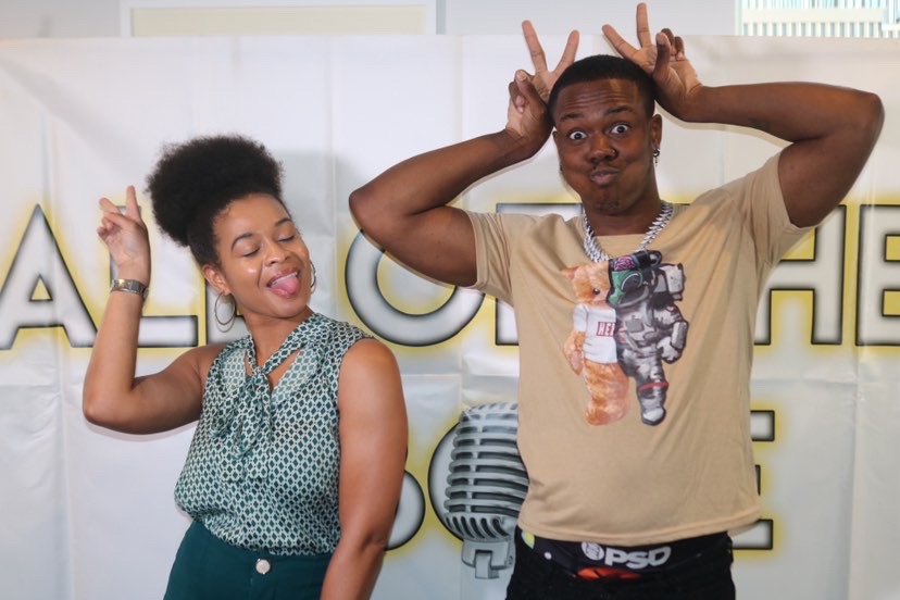 Two people making playful gestures, one with bunny ears and the other with a silly face, in front of a white background with text.