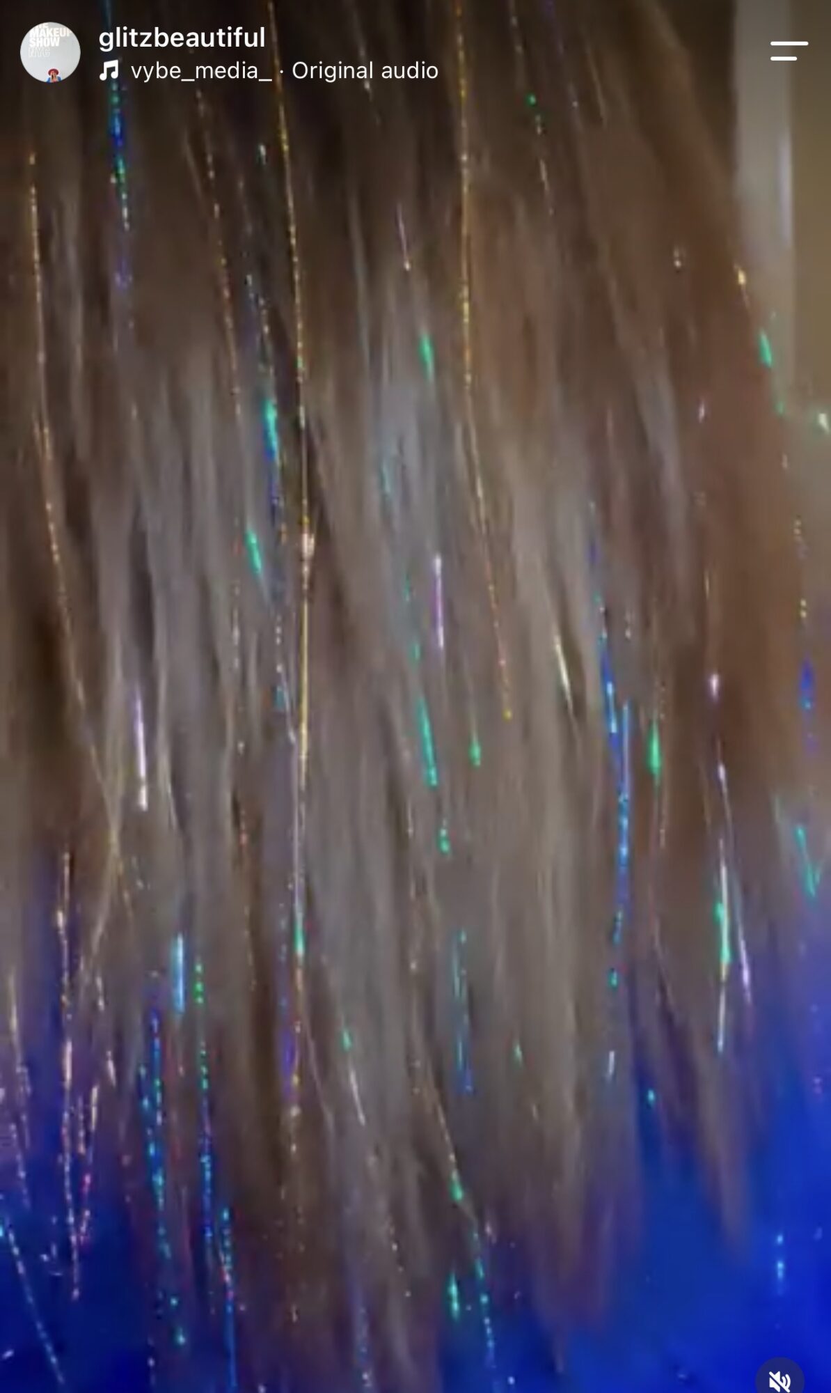 Close-up of hair with colorful light reflections, showing brown and blonde strands with iridescent streaks.