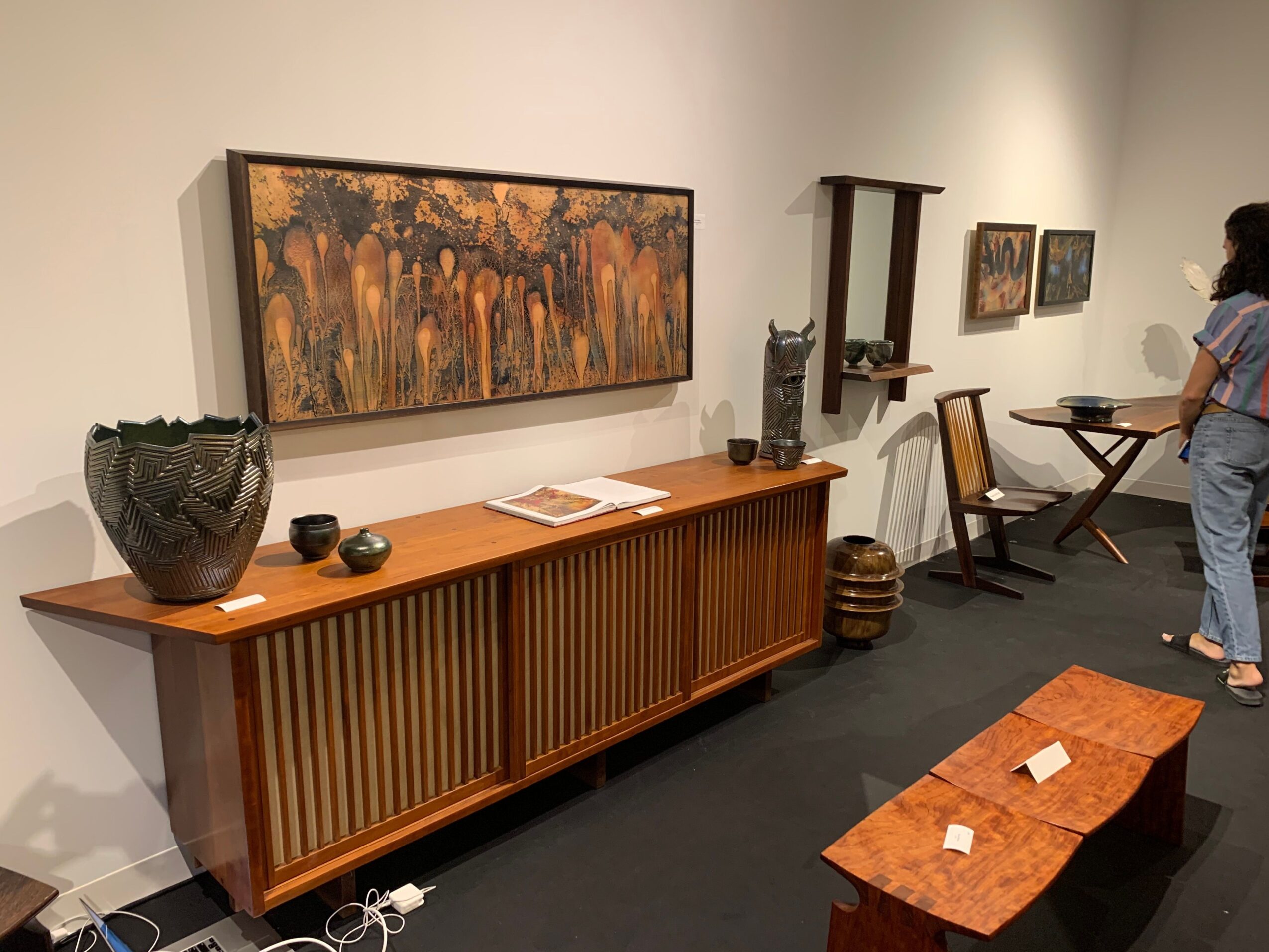 Upside-down view of a room with a large abstract painting, wooden furniture, and decorative items on the wall.