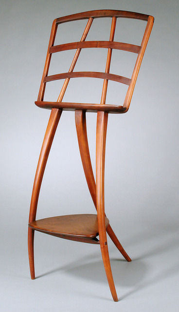 Wooden chair with a curved backrest and a lower shelf, set against a plain background.