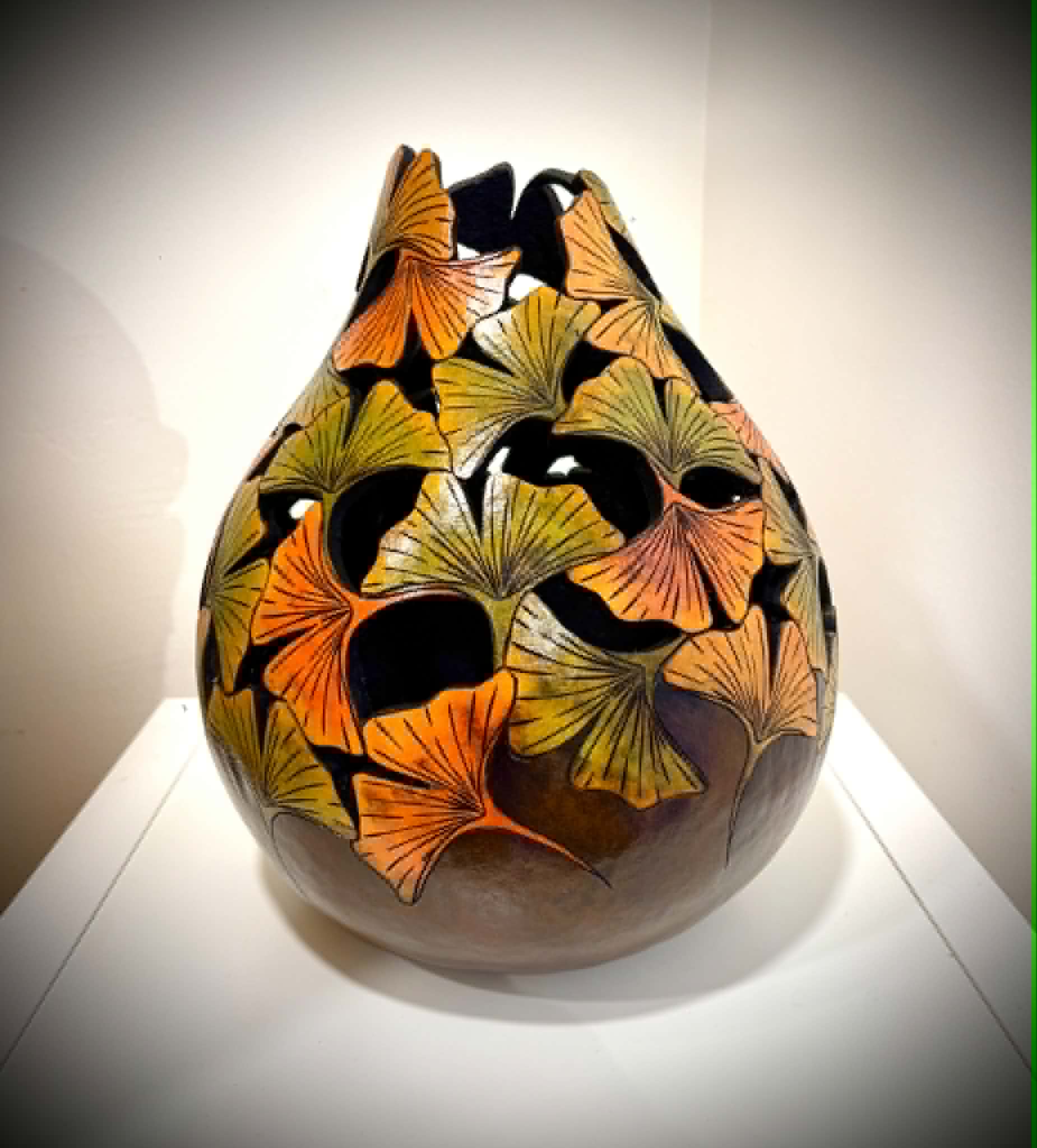 Decorative vase with orange, yellow, and black butterfly patterns on a white surface, against a plain background.