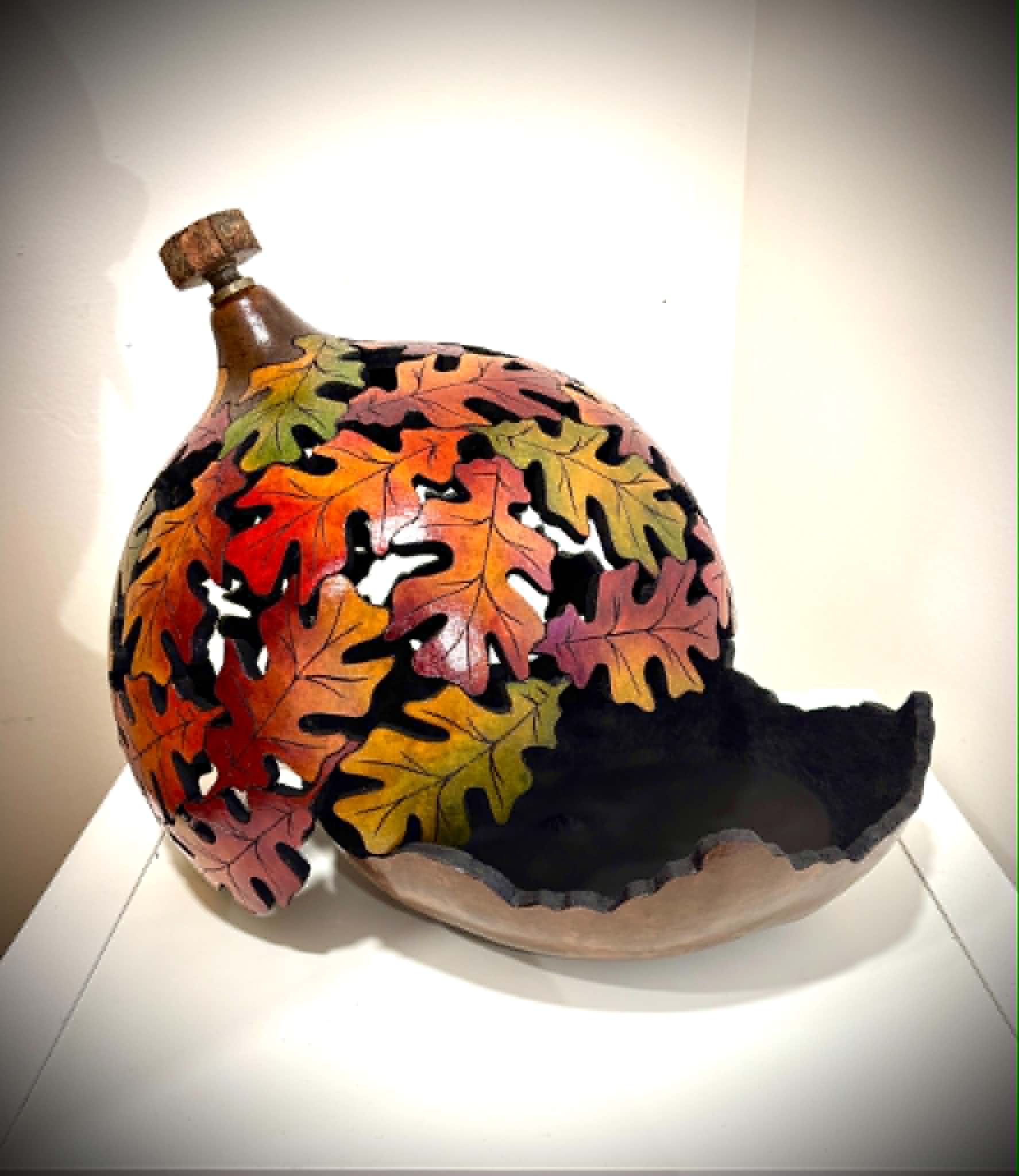 Decorative ceramic piece with colorful autumn leaves and a black base, displayed on a white surface.