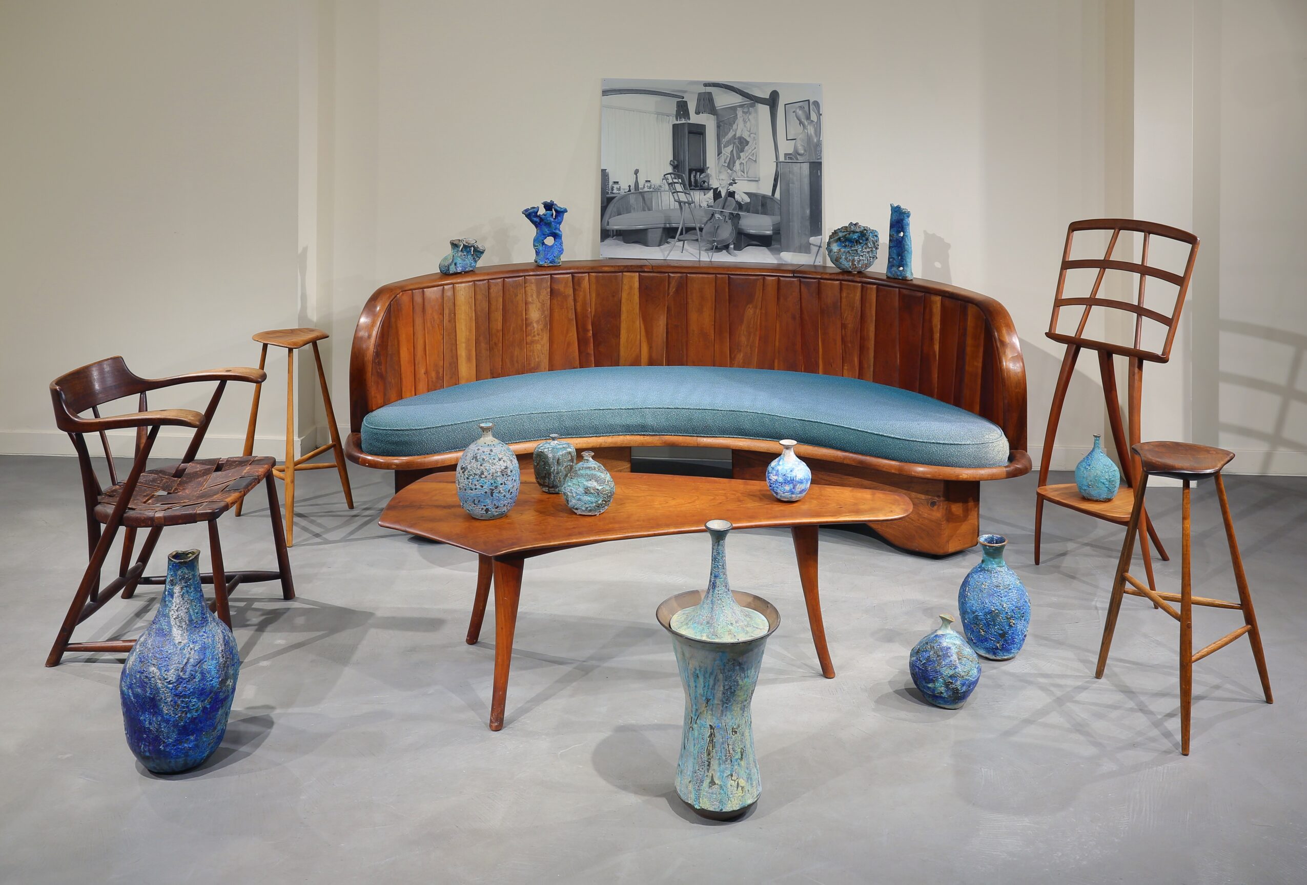 Arrangement of vintage furniture and blue vases in a room with a painting on the wall.