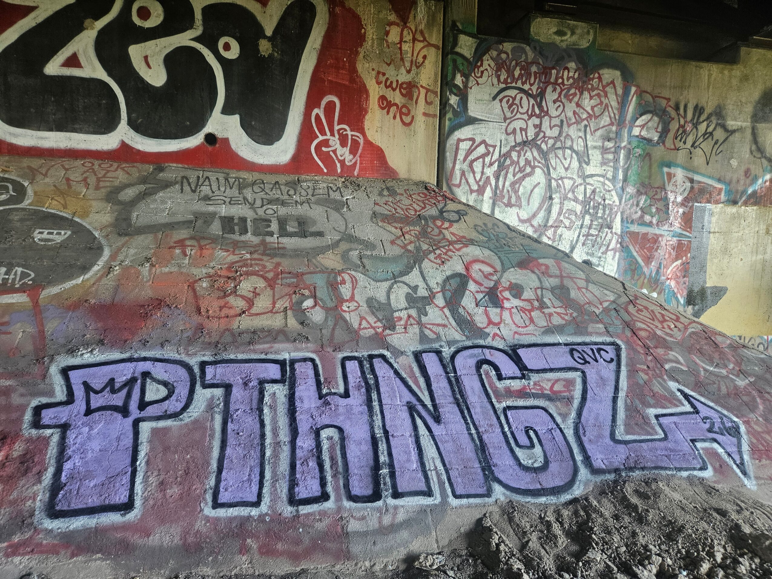 Graffiti with the word 'THING' in purple and black on a concrete surface, surrounded by colorful wall graffiti.