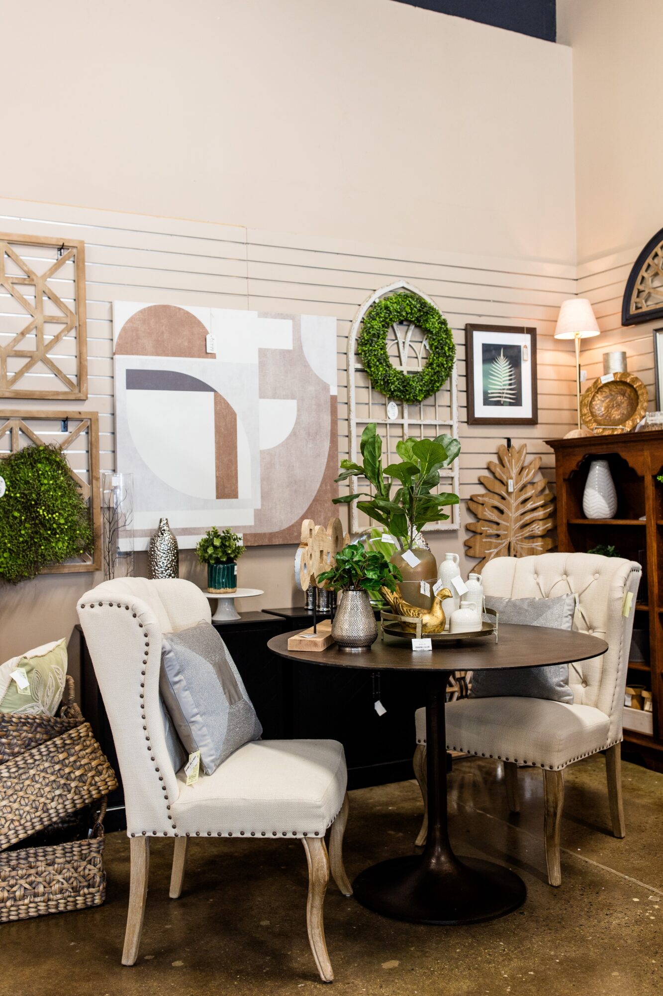 Interior dining area with wall art, framed pictures, plants, and a round table with chairs.