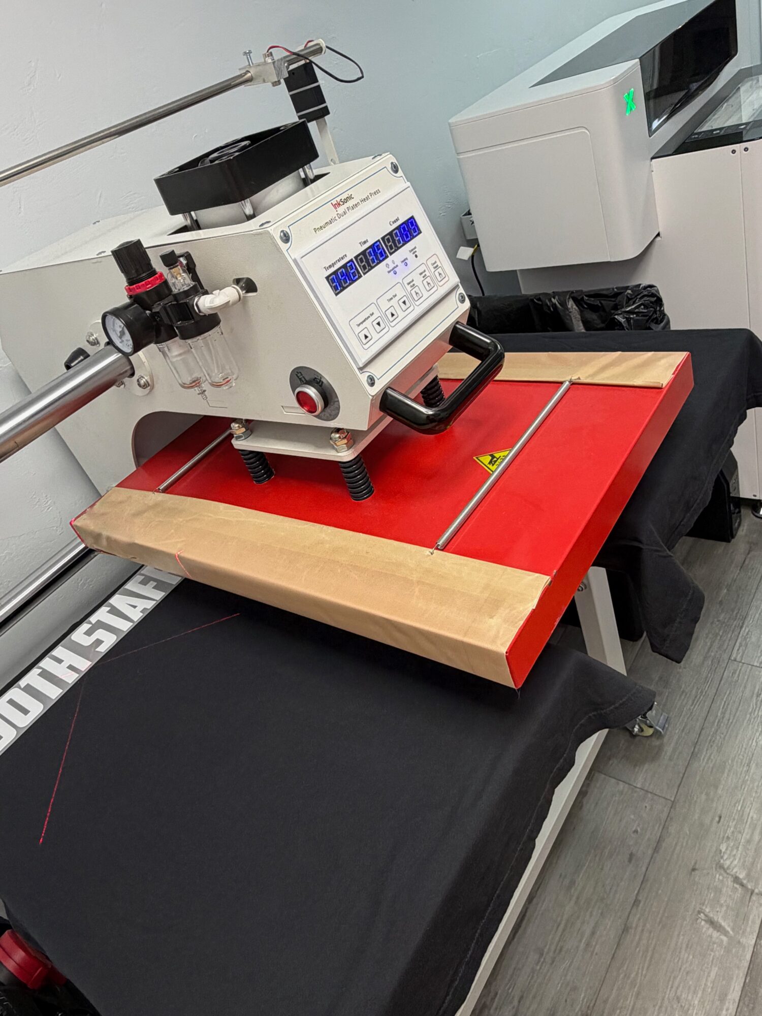 Laboratory machine with a digital display and a robotic arm on a red and black table.