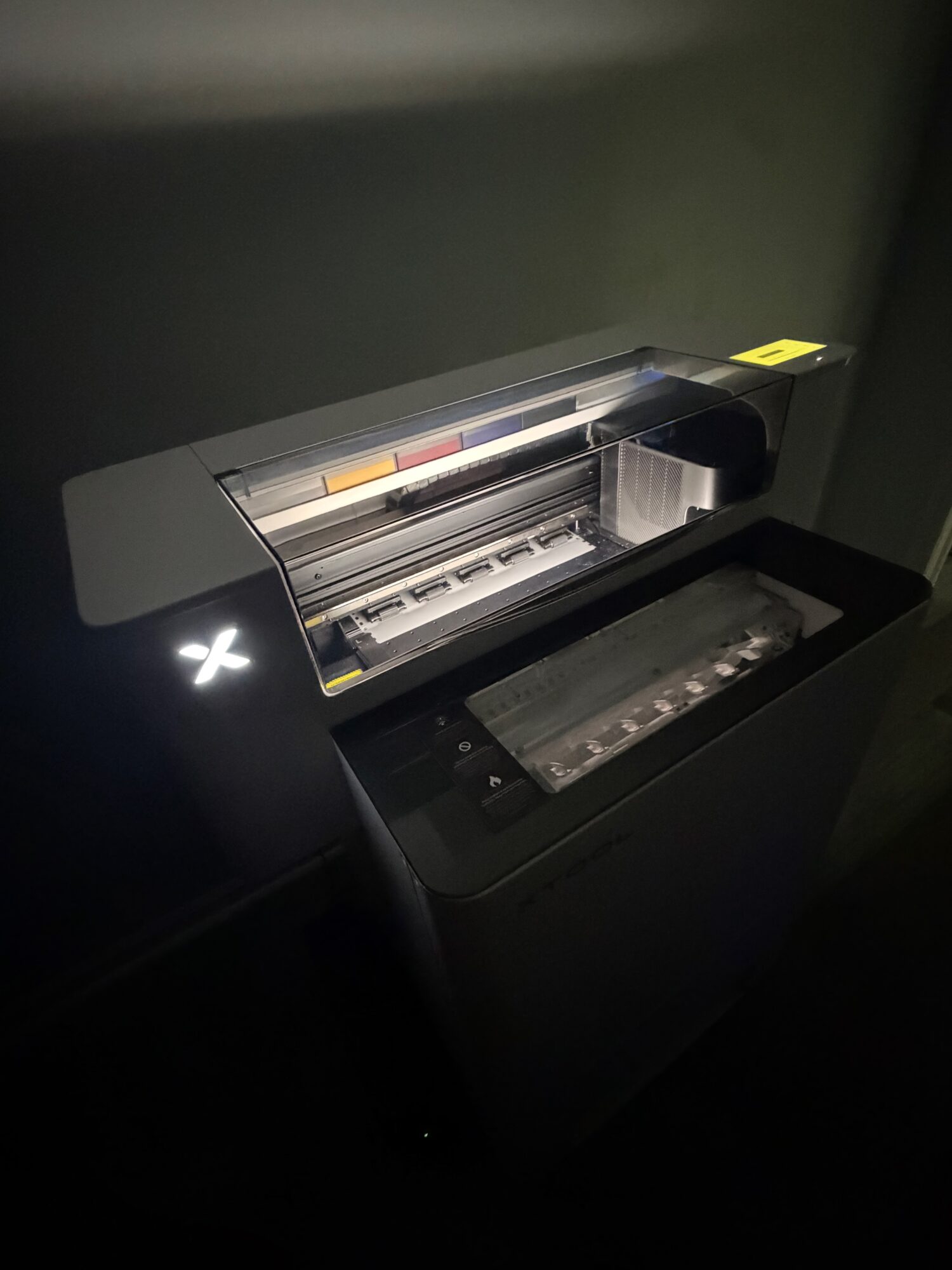 Photocopier or printer with paper tray and control panel, in a dimly lit room.