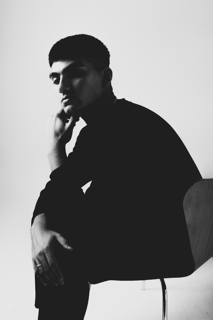 Silhouette of a person sitting with hand on chin, facing left, in black and white.