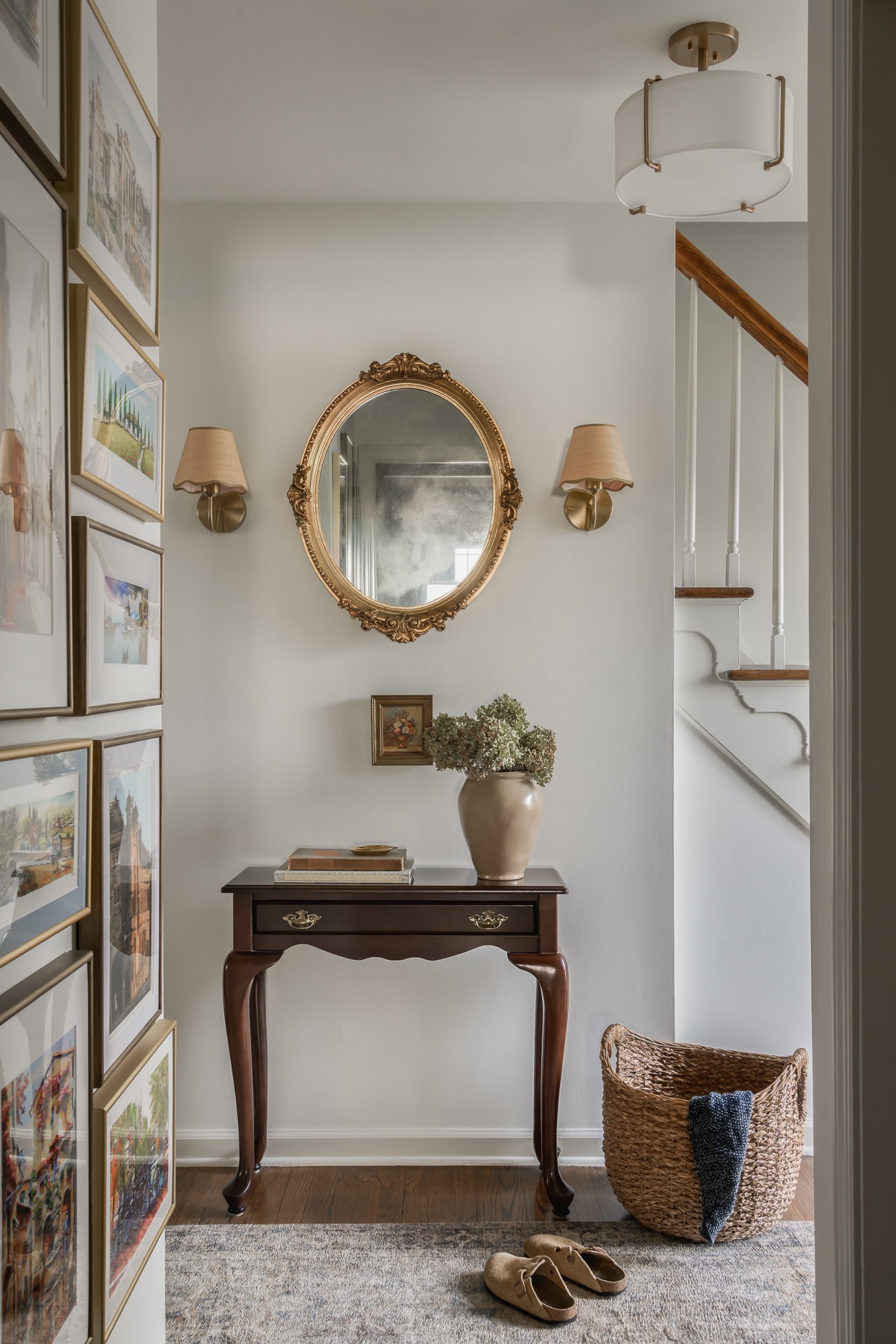 Entryway with a mirror, wall sconces, a small table with a plant, and a basket on the floor.