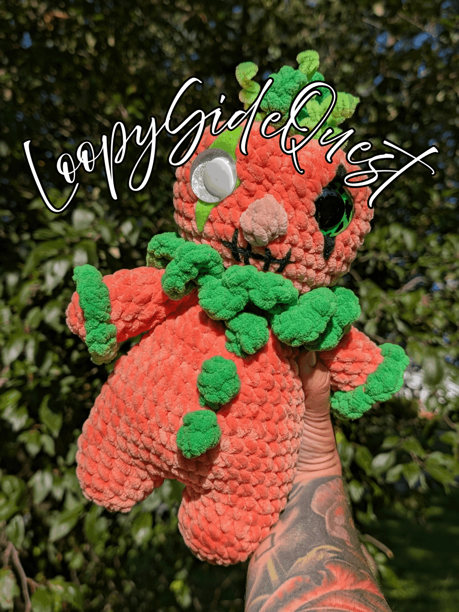 Hand holding a colorful plush toy with a background of green foliage, and text reading