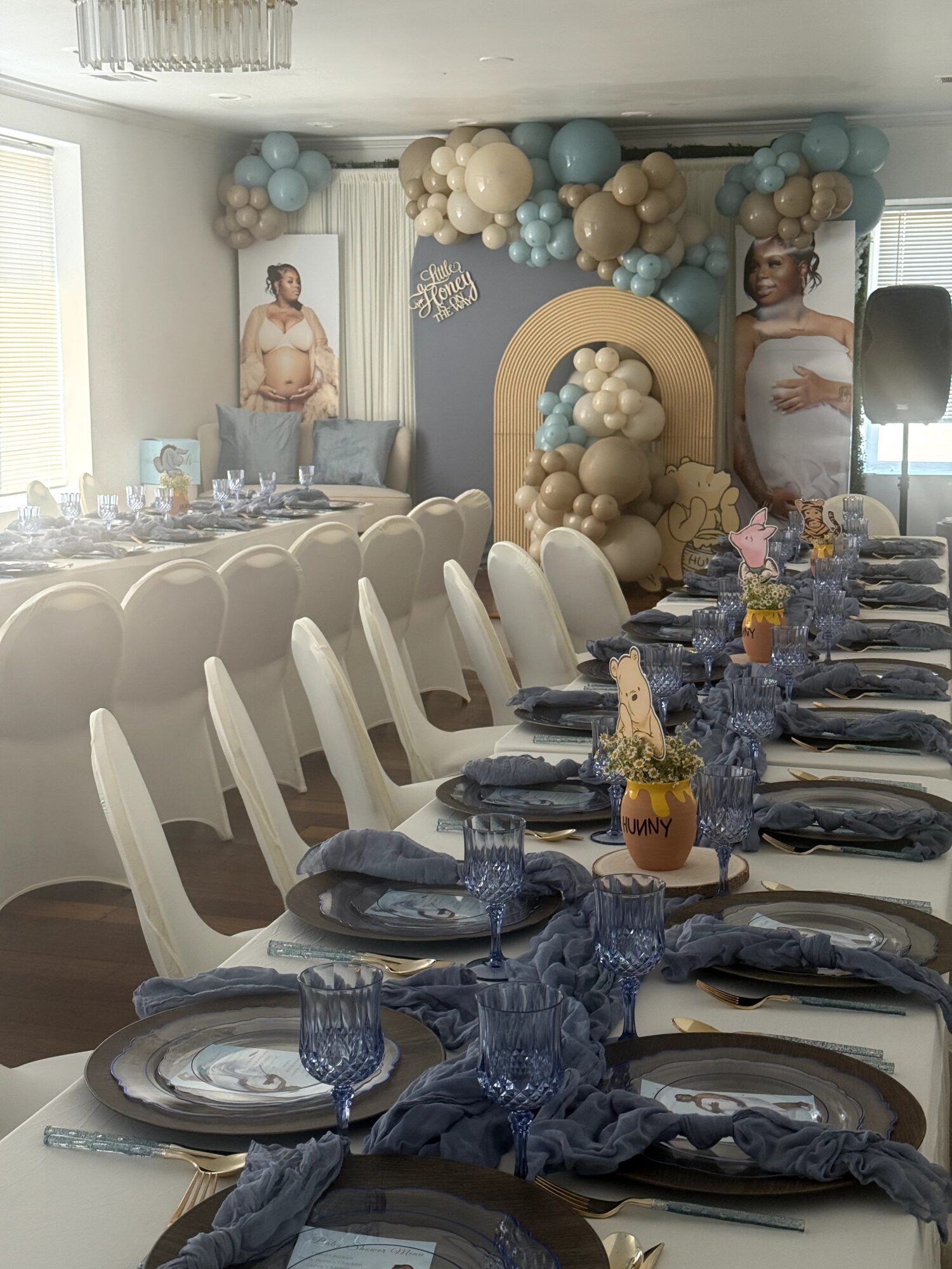 Decorated banquet room with long table, white chairs, blue and gold balloons, and a backdrop with a large number 0 and balloons.