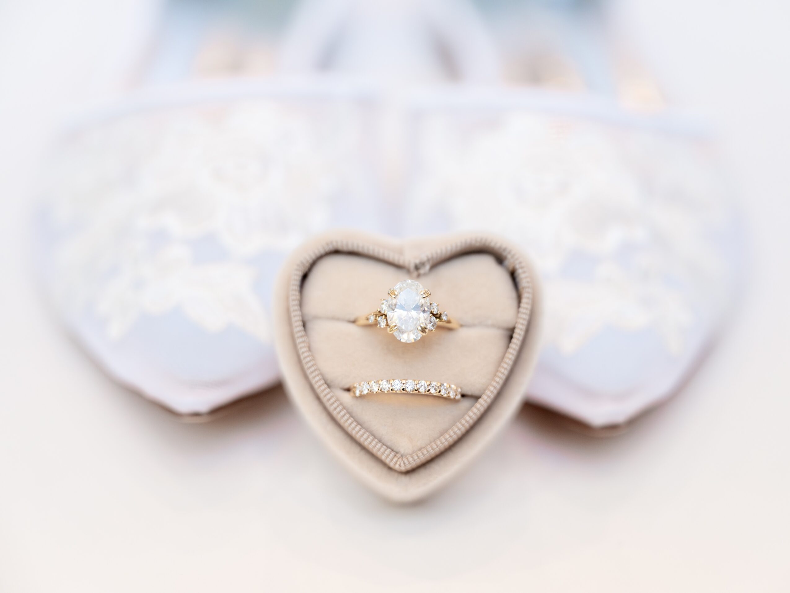 Heart-shaped jewelry box with a ring and bracelet inside, background of white lace fabric, soft focus