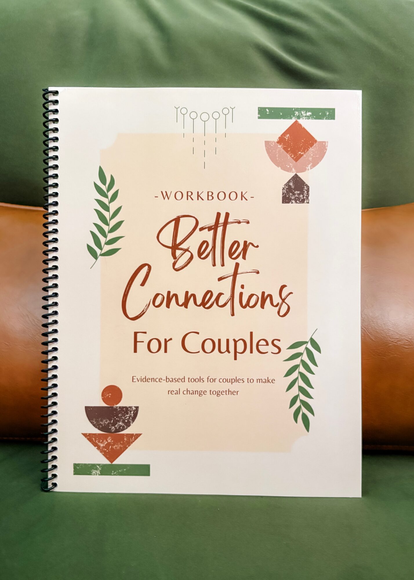 Workbook titled 'Better Connections for Couples' with decorative leaves and geometric shapes, placed on a green and brown background.