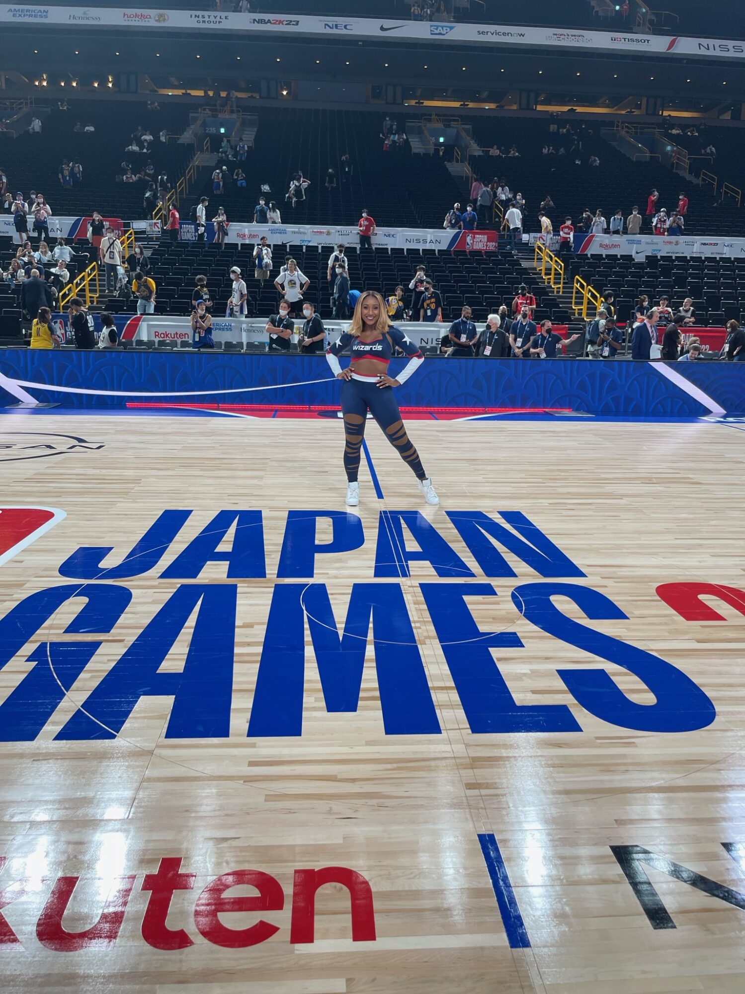 A person standing on a basketball court with 'JAPAN GAMES' written on the floor, surrounded by spectators in the stands.
