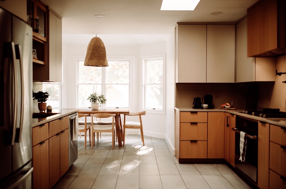 Kitchen with wooden cabinets, a dining table with chairs, and large windows letting in natural light.
