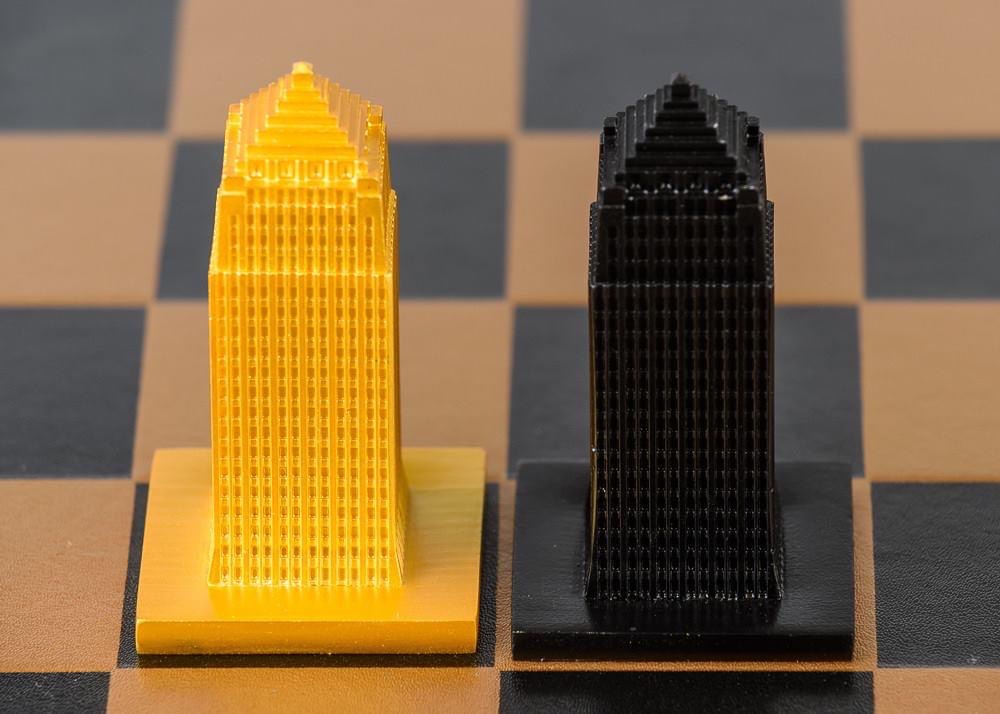 Two chess rooks, one yellow and one black, placed on a chessboard, facing forward.