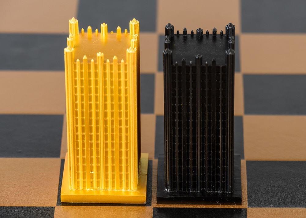 Two vertical plastic objects, one yellow and one black, with multiple vertical fins, placed on a checkered surface.