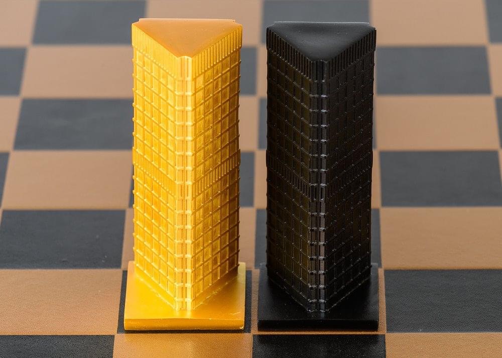 Two tall, rectangular objects, one yellow and one black, stand on a checkered surface.