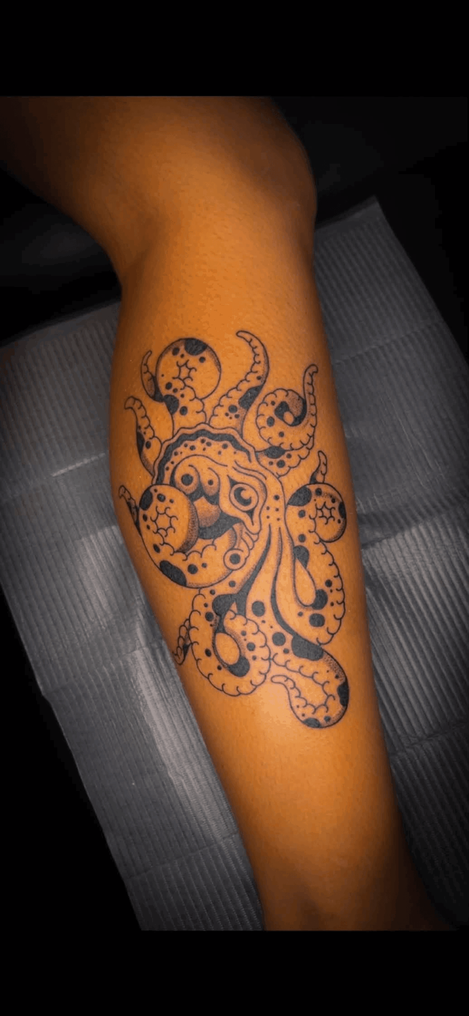 Tattoo of an octopus with detailed tentacles on person's forearm, black ink design, skin visible.