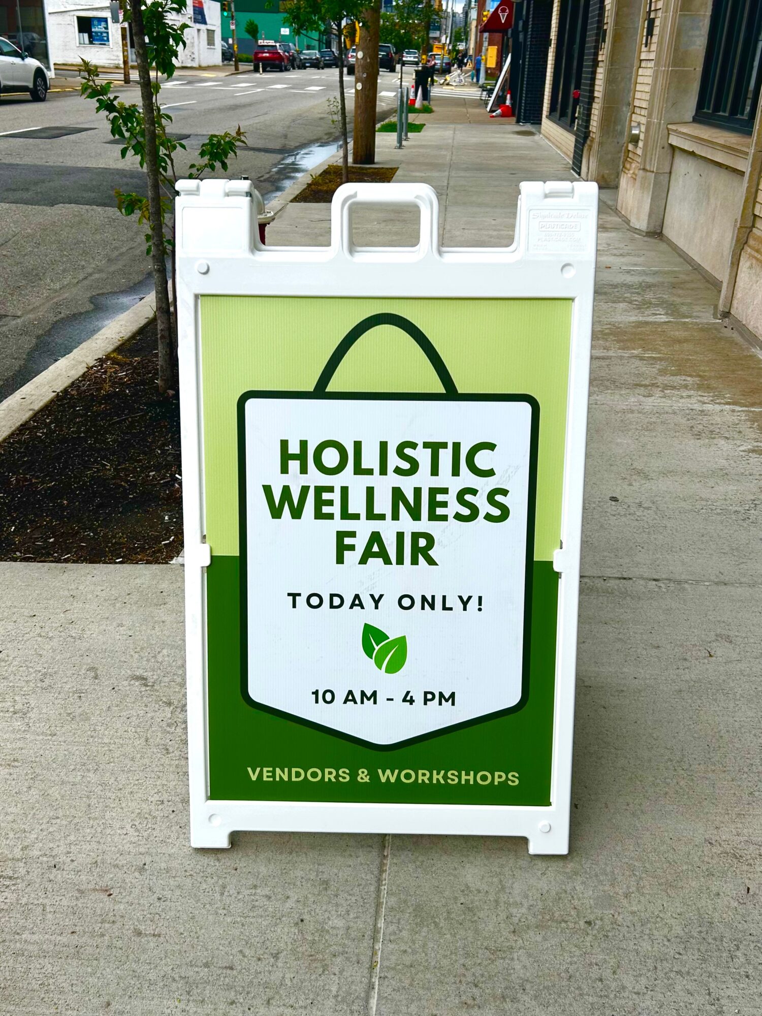 Signboard advertising a holistic wellness fair with vendors and workshops, open today from 10 AM to 4 PM.